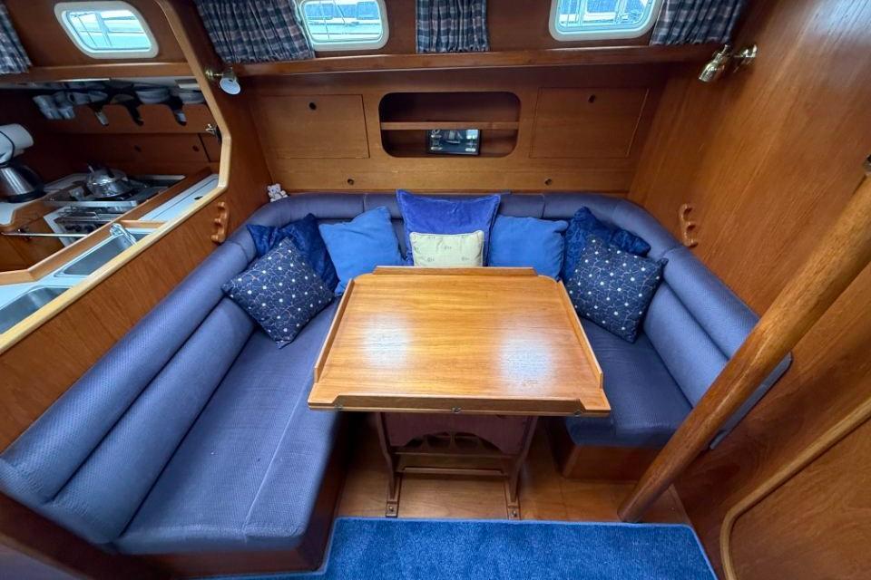 Cozy interior of a 1994 Bowman 40 yacht with wooden table and blue cushions.