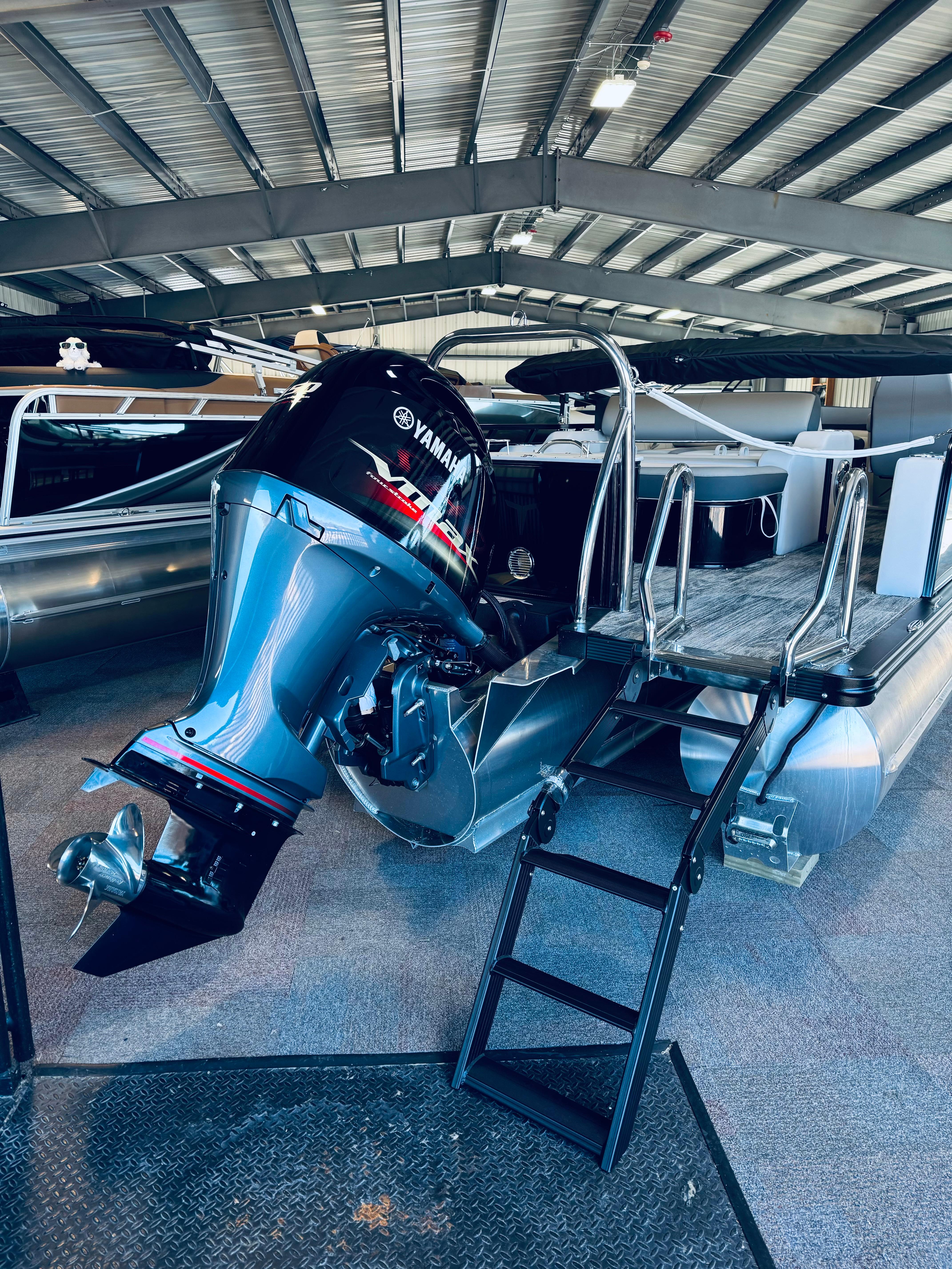 2025 Tahoe Pontoon LTZ Versatile Rear Bench with Yamaha outboard motor in a showroom.