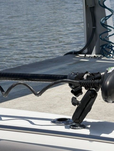 Boston Whaler 330 Outrage 2023 with fishing rod holder by the water.