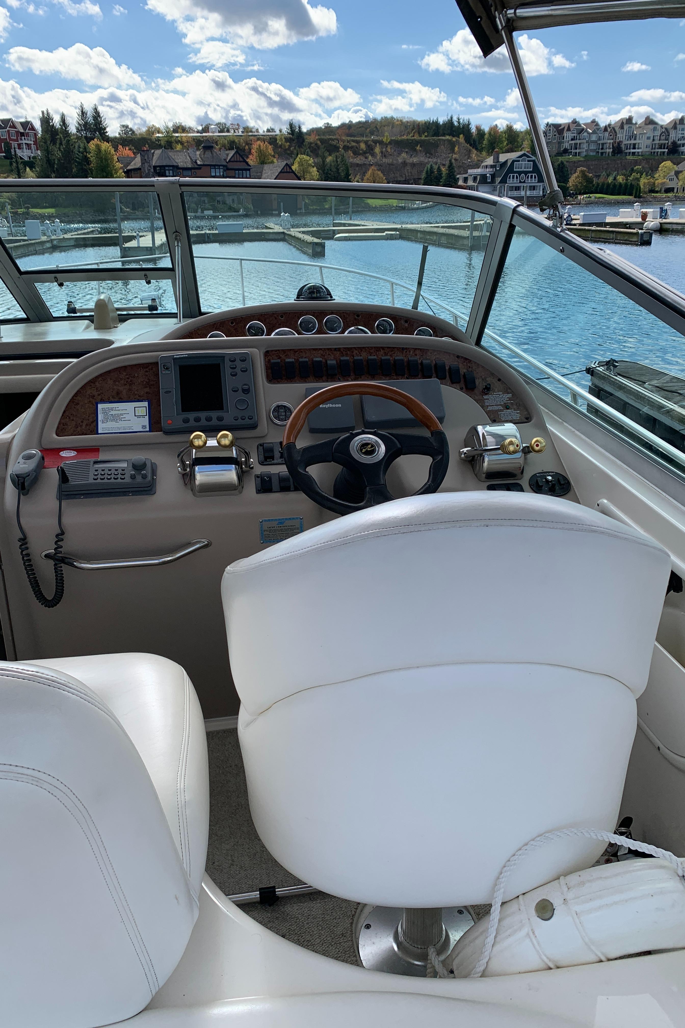 2001 Sea Ray 310 Sundancer helm with scenic waterfront view.