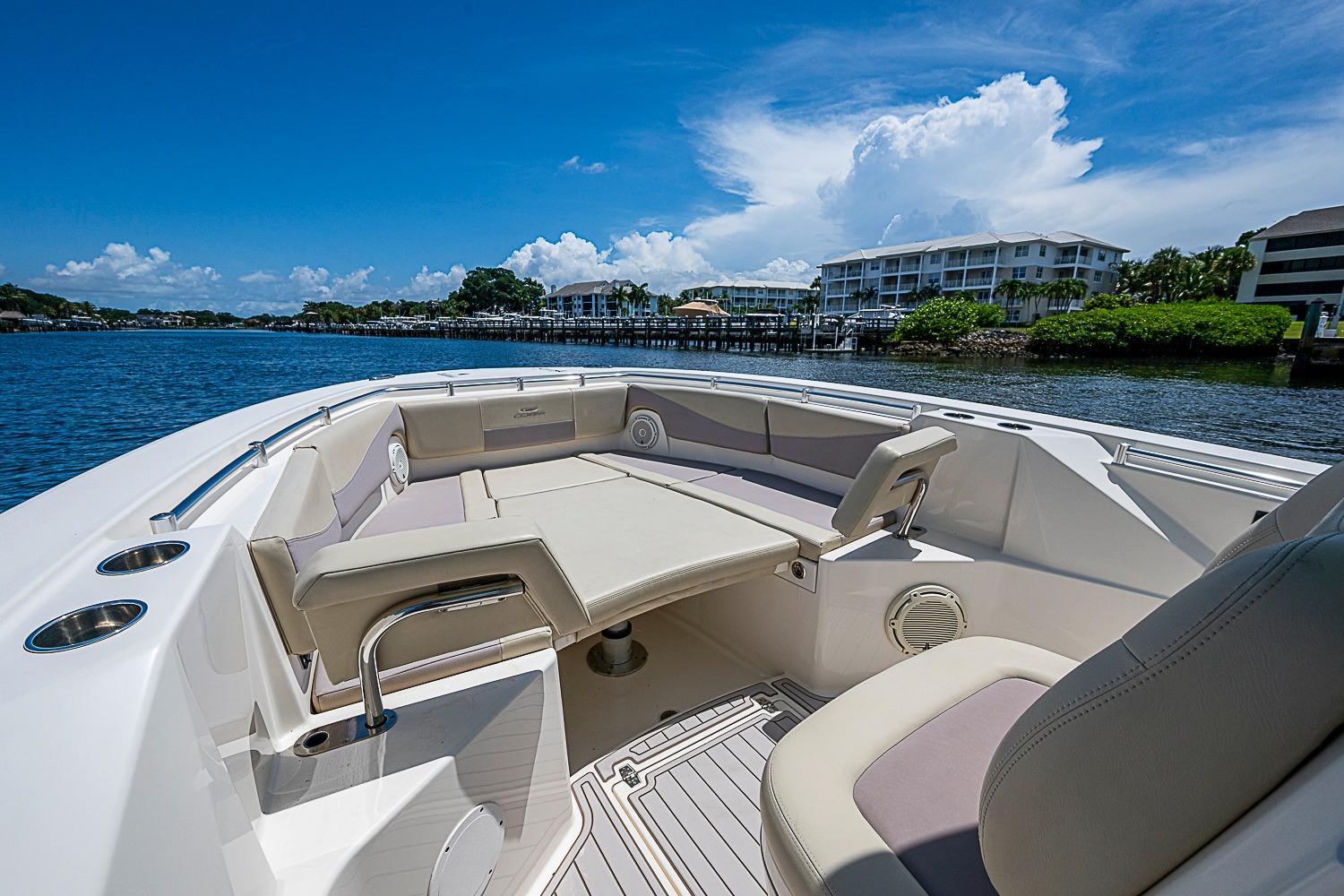 2019 Cobia 320 Center Console boat with spacious seating, docked by waterfront homes.