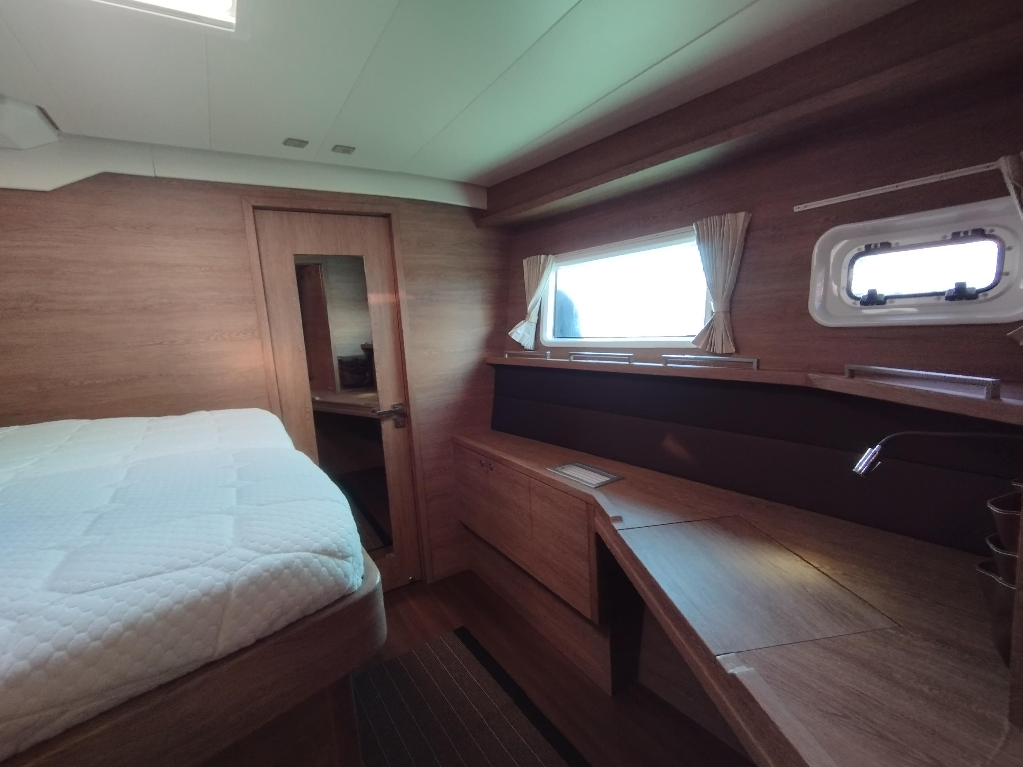 Luxurious interior of 2012 Lagoon 620 yacht cabin with wooden furnishings and natural light.