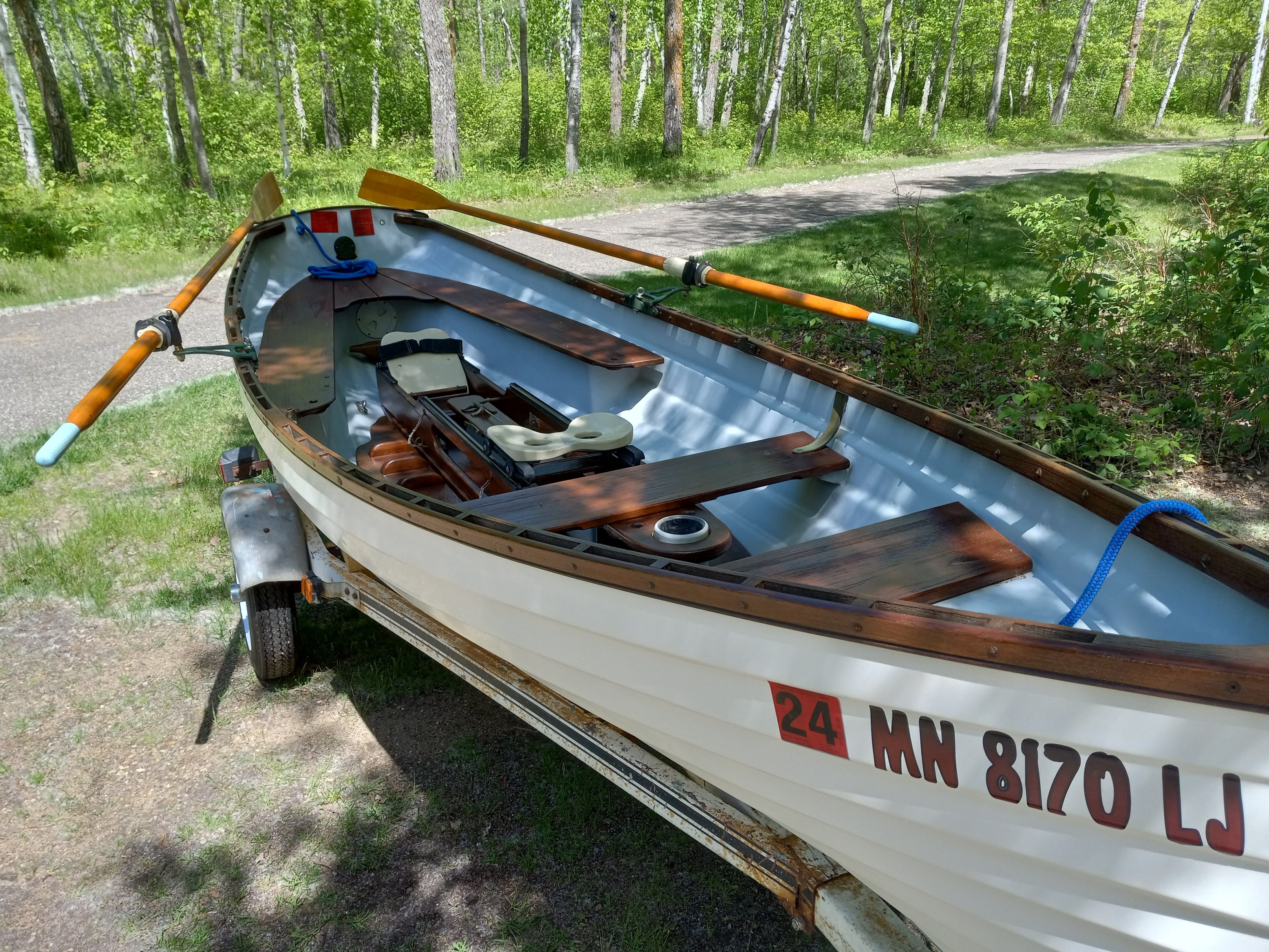 A 2005 Whitehall Spirit 14 rowing boat on a trailer in a wooded area.