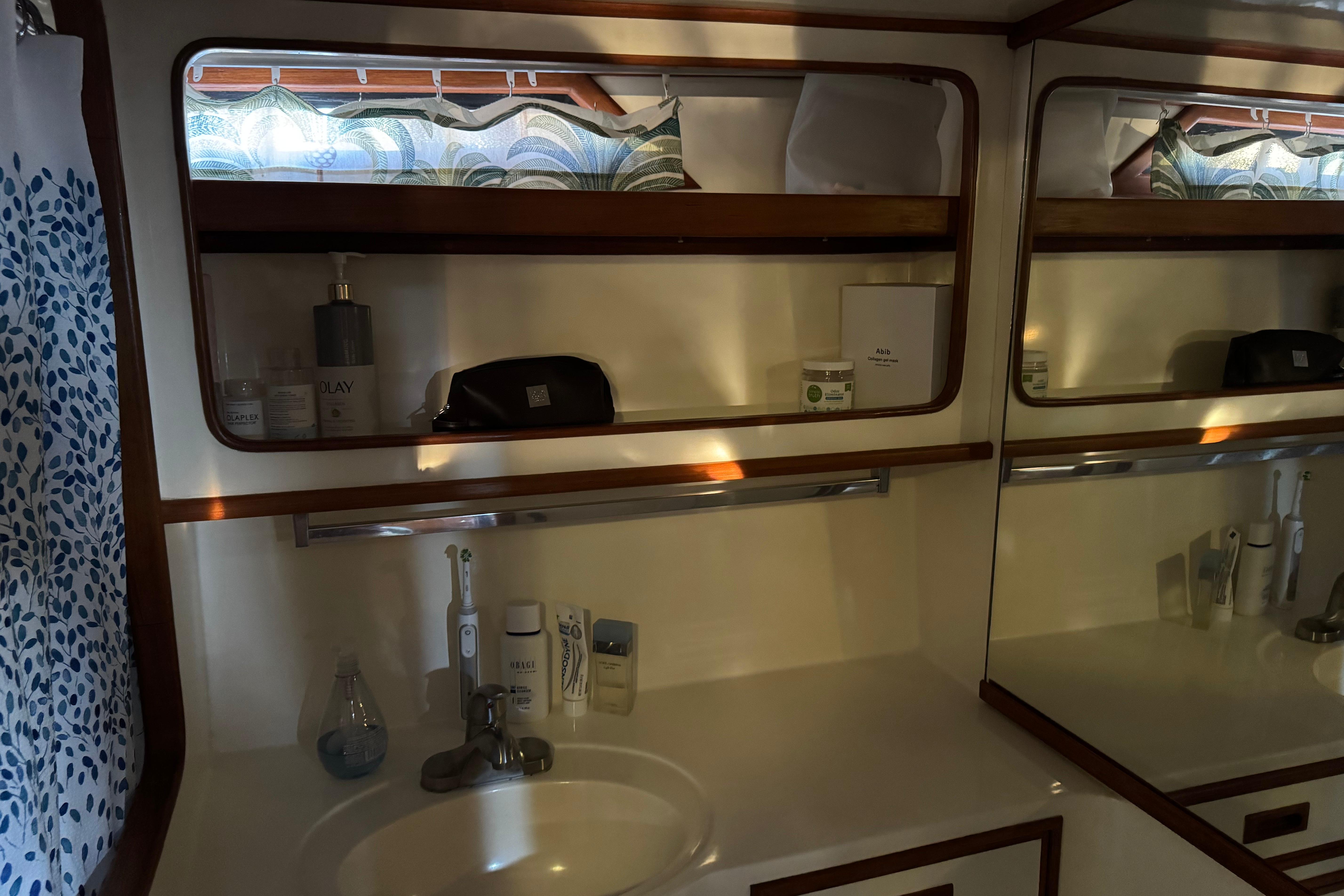 1987 President 37 yacht bathroom with sink, mirror, and toiletries on shelves.