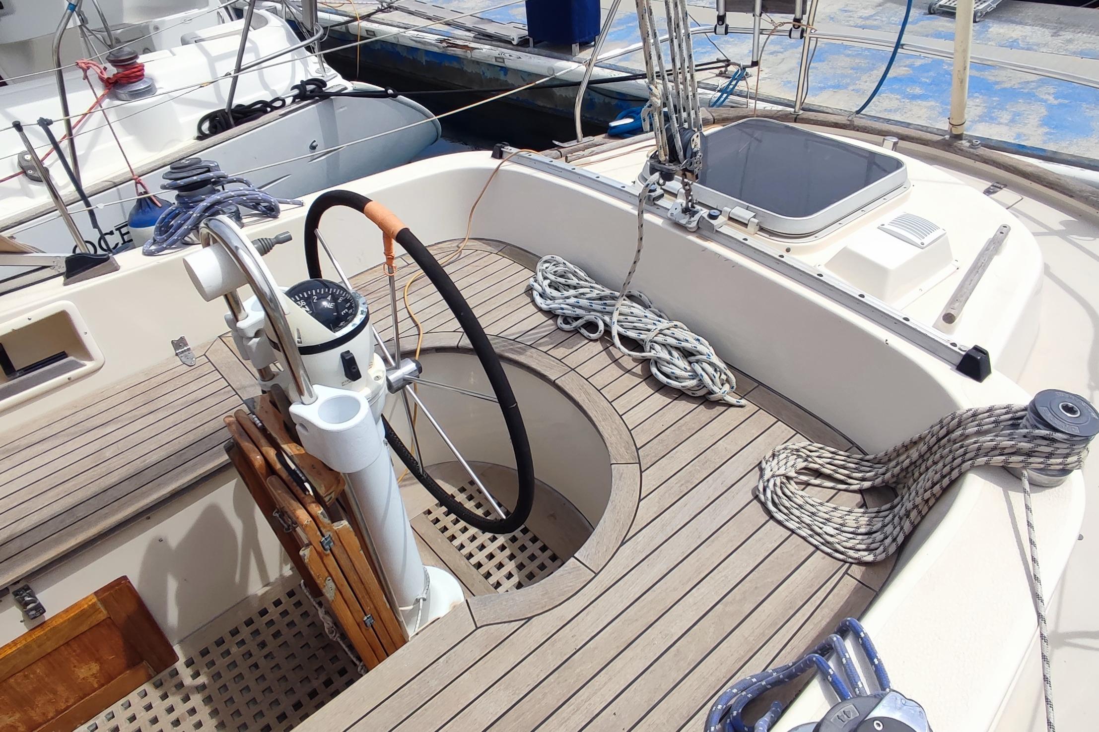 Cockpit of 1982 Hallberg-Rassy 352 sailboat with steering wheel and ropes.