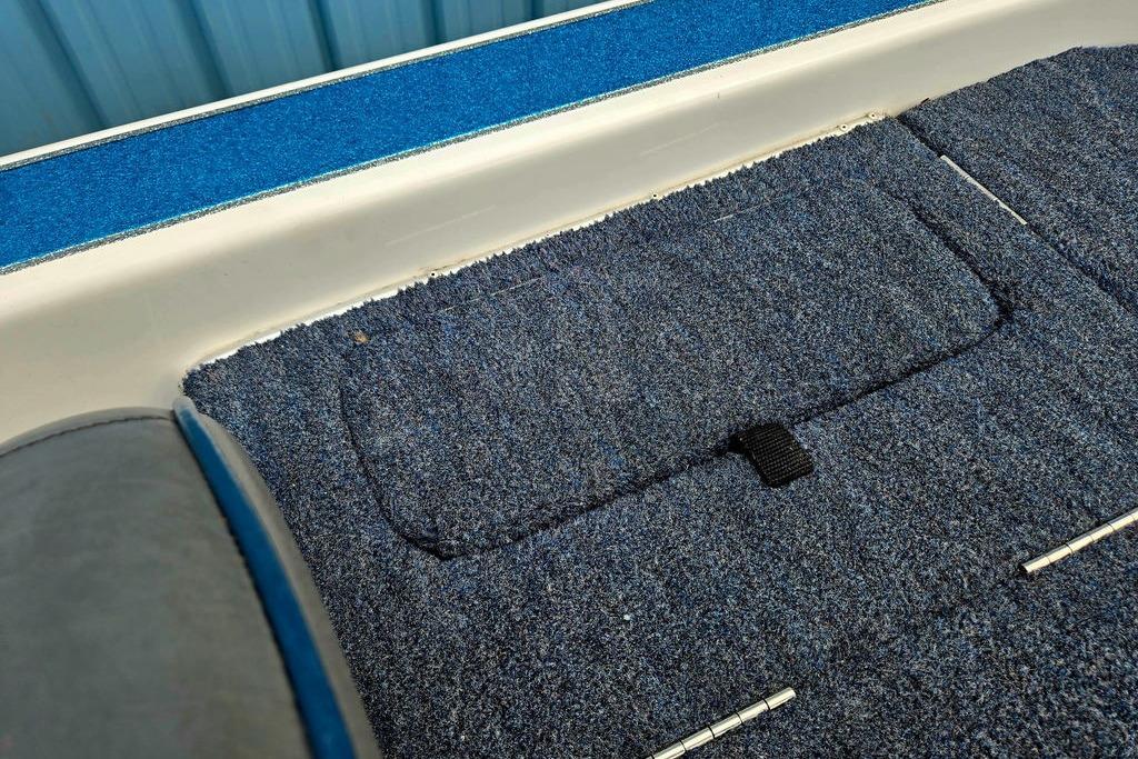 Interior of a 1996 Champion 181 SX boat with blue carpet and storage compartment.