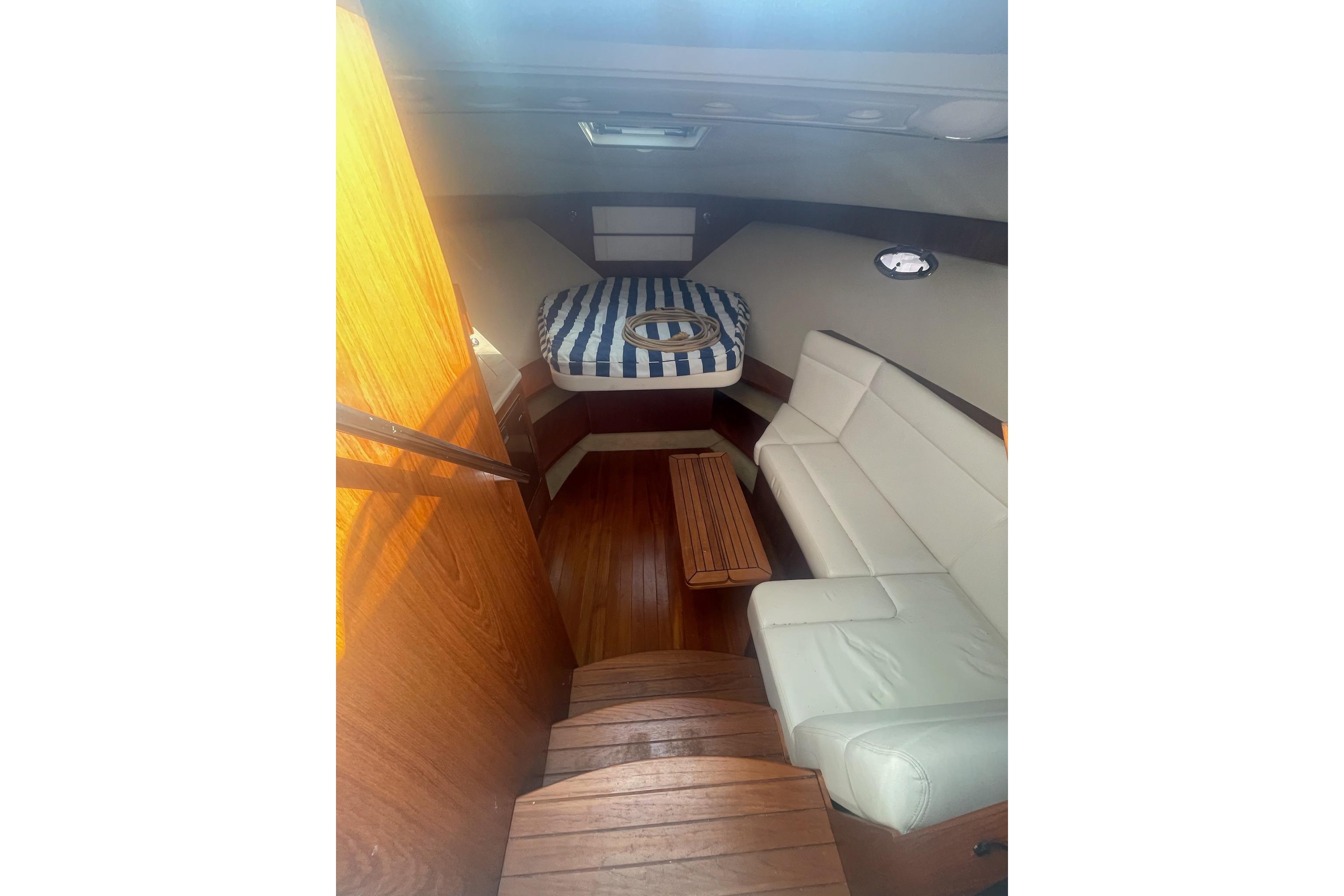 2013 Tiara Yachts 3100 Open cabin interior with seating and striped bedding.