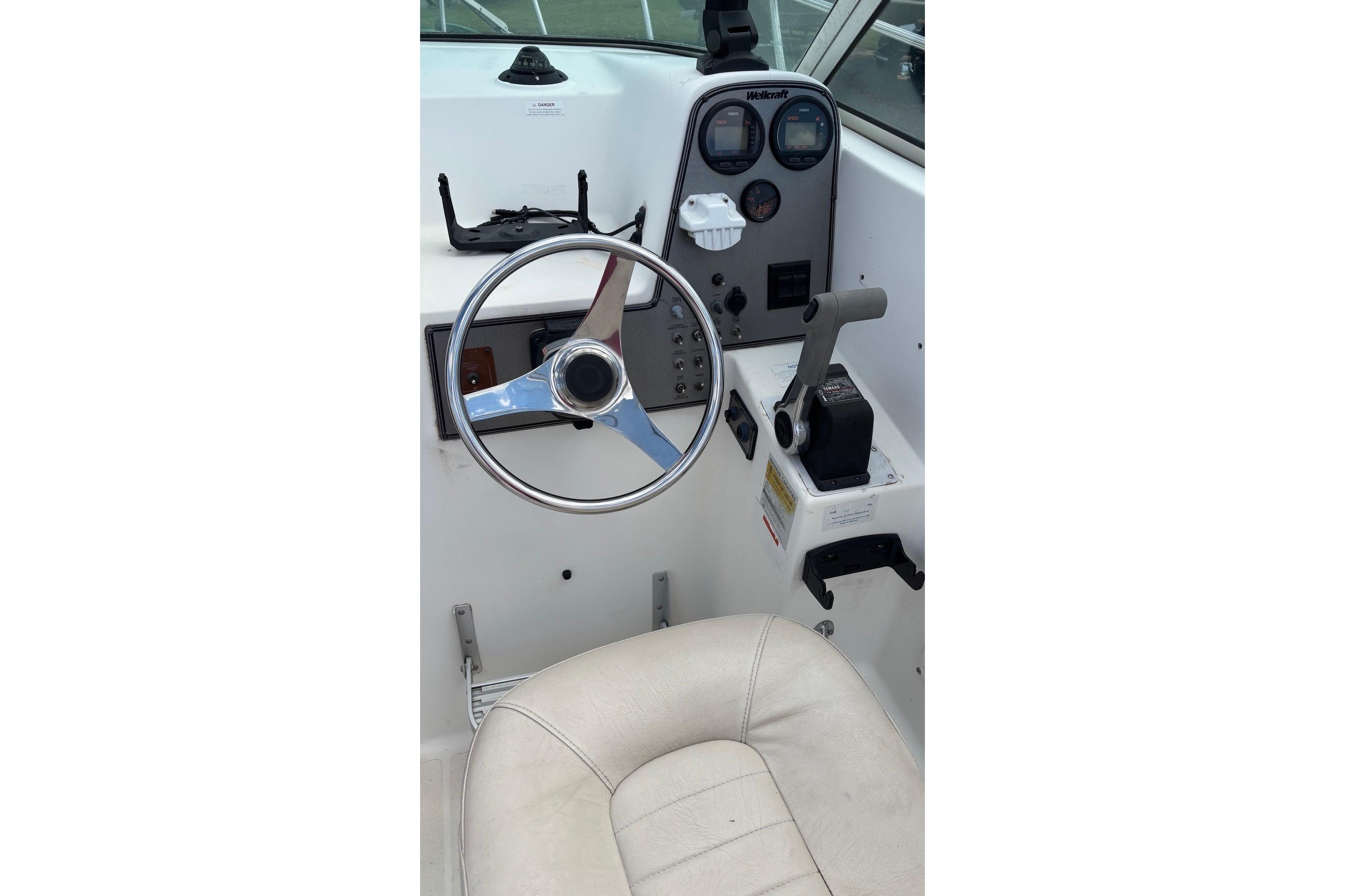 2002 Wellcraft 24 Walkaround boat cockpit with steering wheel and controls.