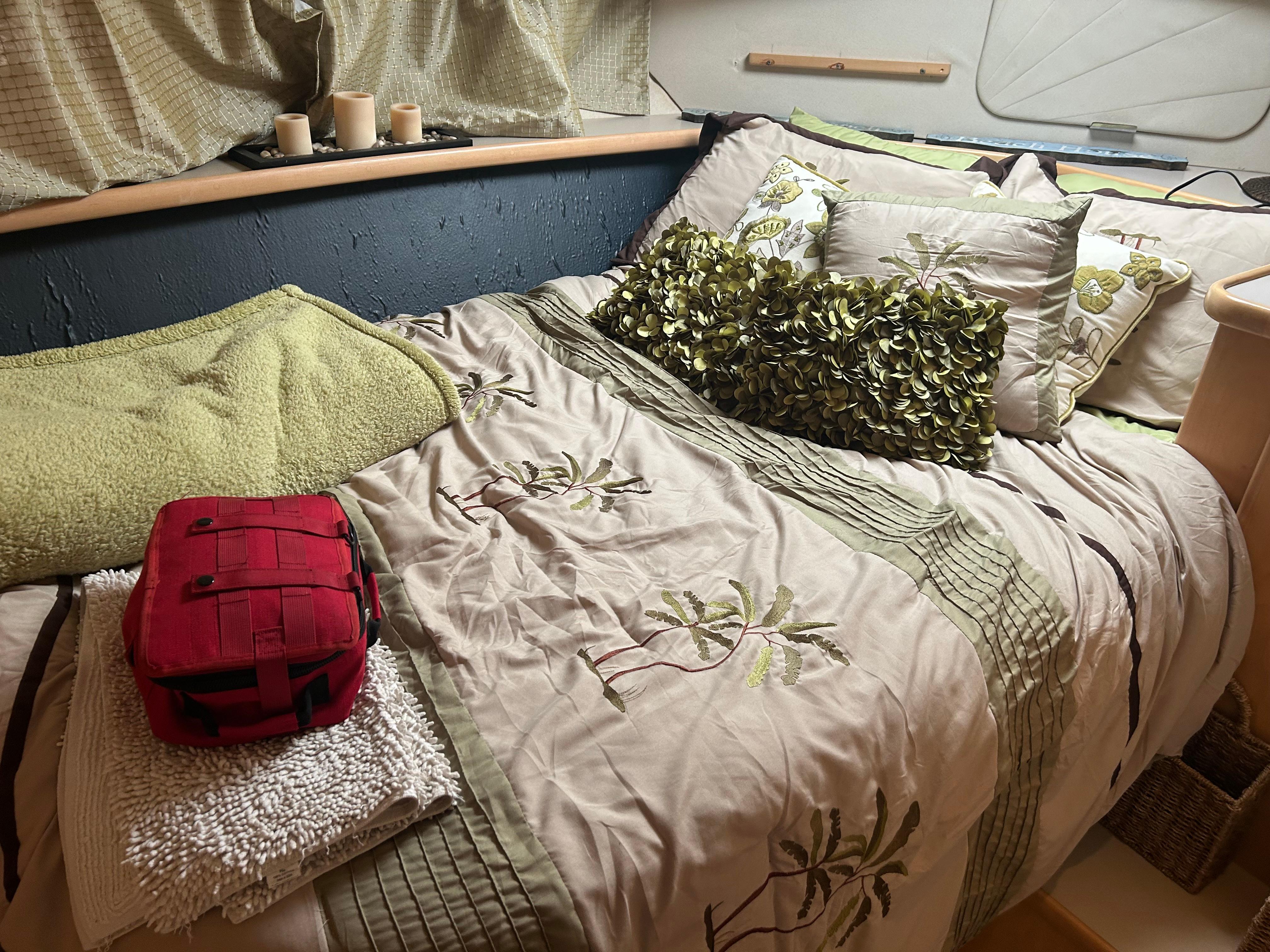 Cozy bedroom in 1996 Carver 440 Aft Cabin Motor Yacht with decorative pillows and a red bag.