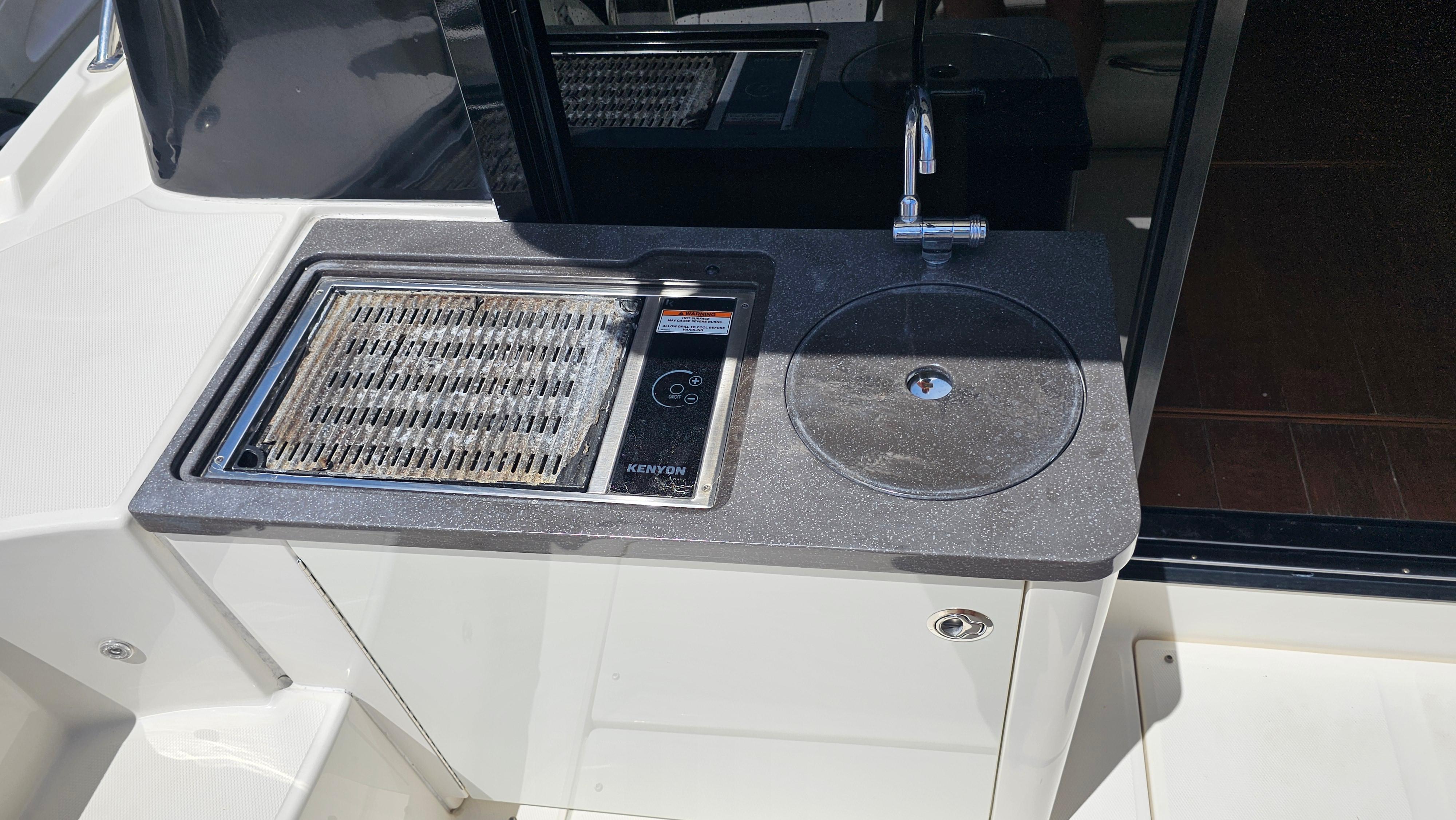 Outdoor kitchenette on 2016 Sea Ray 470 Sundancer yacht with grill and sink.