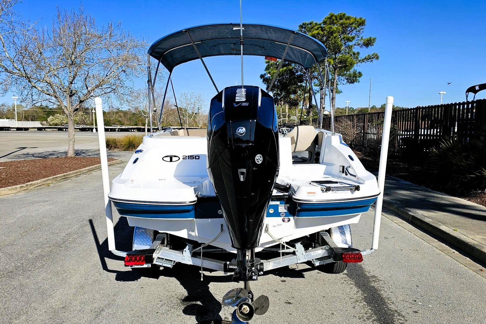 2026 Tahoe 2150 boat with outboard motor on a trailer in a parking lot.