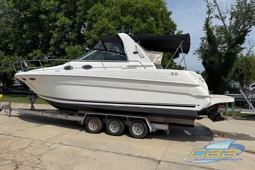 1999 Sea Ray 290 Sundancer boat on trailer, parked outdoors with trees in background.