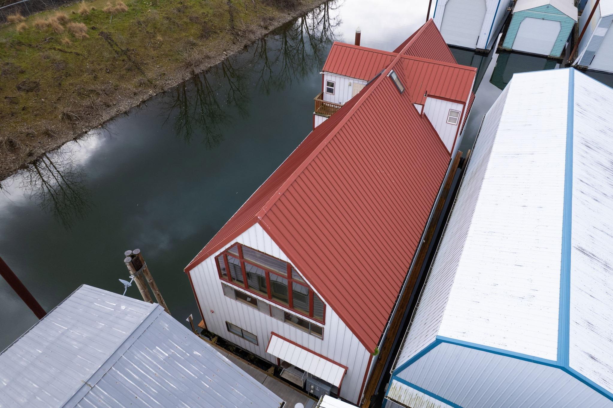Aerial view of a 1976 custom boathouse with red roof by a calm river.
