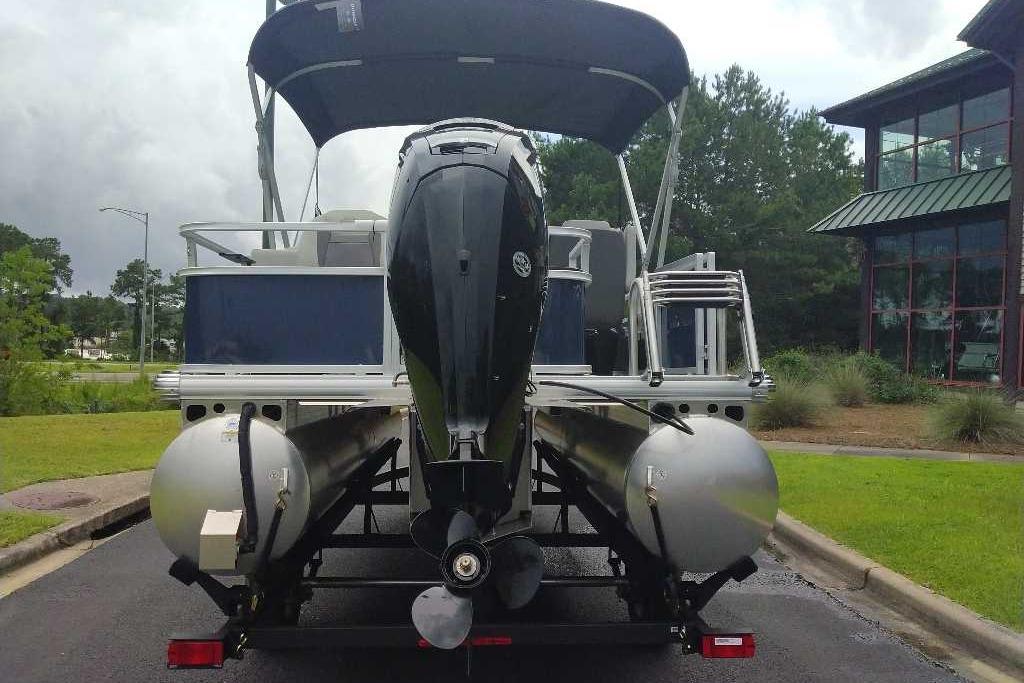 2026 Sun Tracker Bass Buggy 18 DLX pontoon boat with outboard motor, parked outdoors.