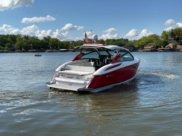 Red 2022 Cobalt A36BR boat cruising on a lake under a clear blue sky.