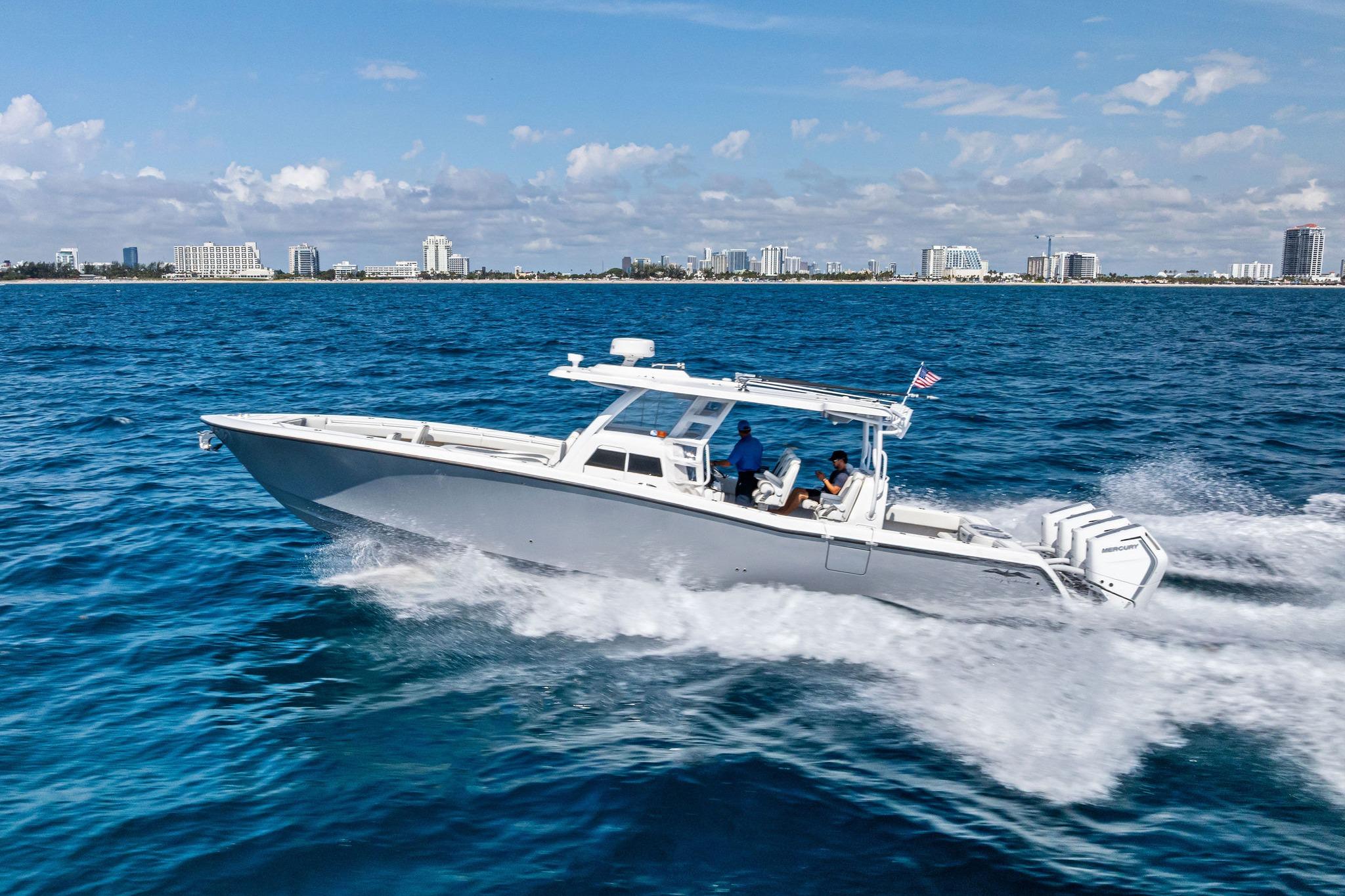 2024 Invincible 43 Open Fisherman cruising on blue ocean near city skyline.