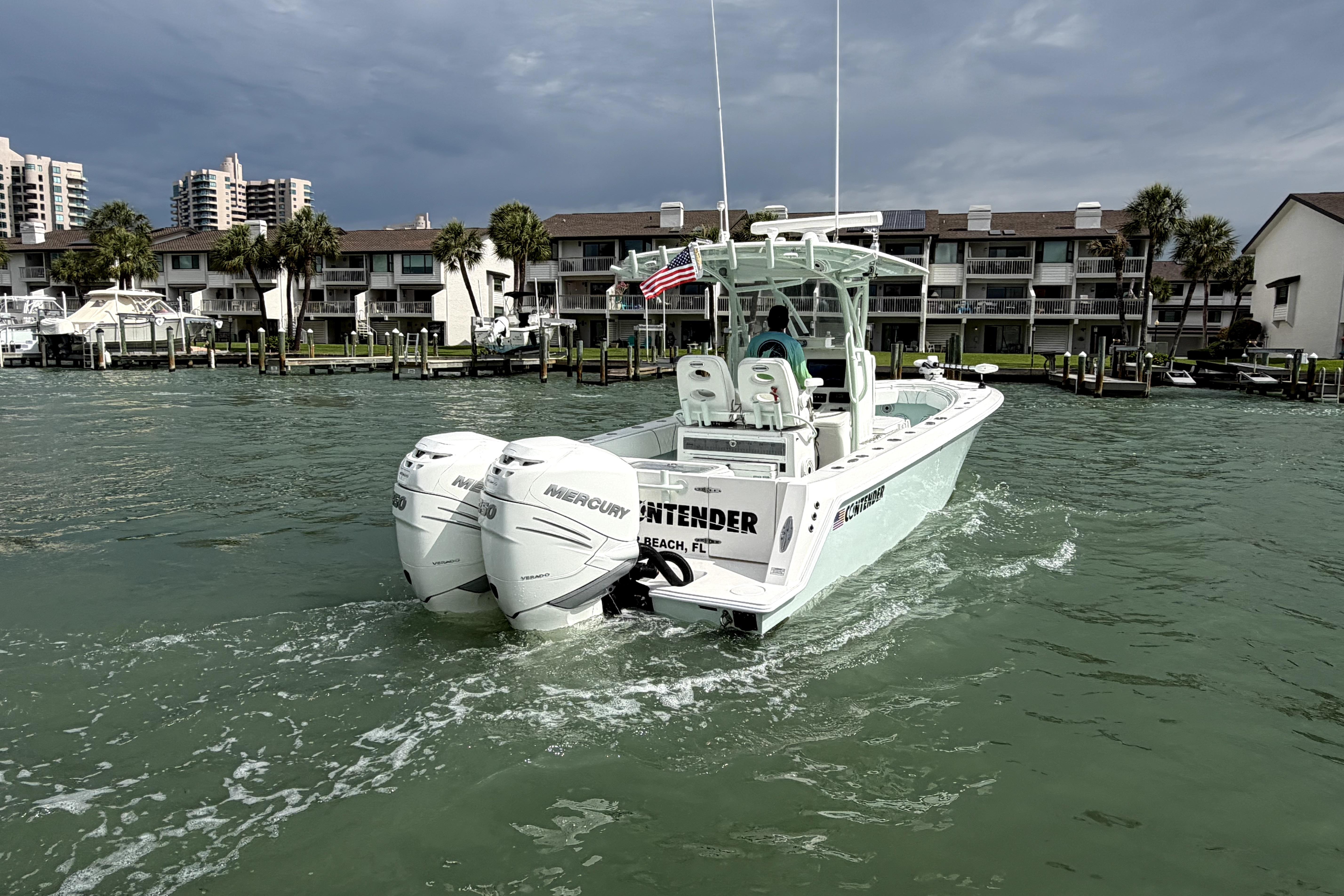 2019 Contender 30 ST boat with twin Mercury engines cruising near waterfront homes.