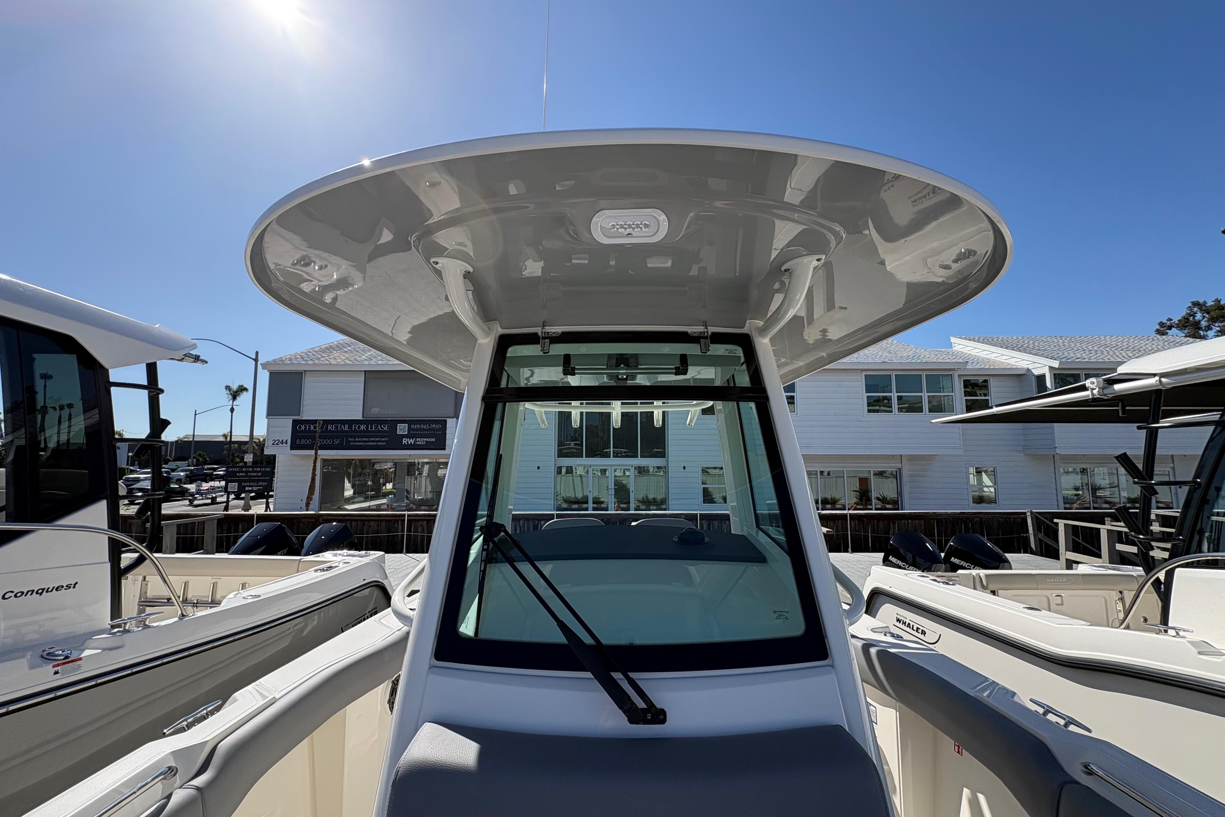 2026 Boston Whaler 280 Outrage boat, showcasing helm and T-top under clear blue sky.
