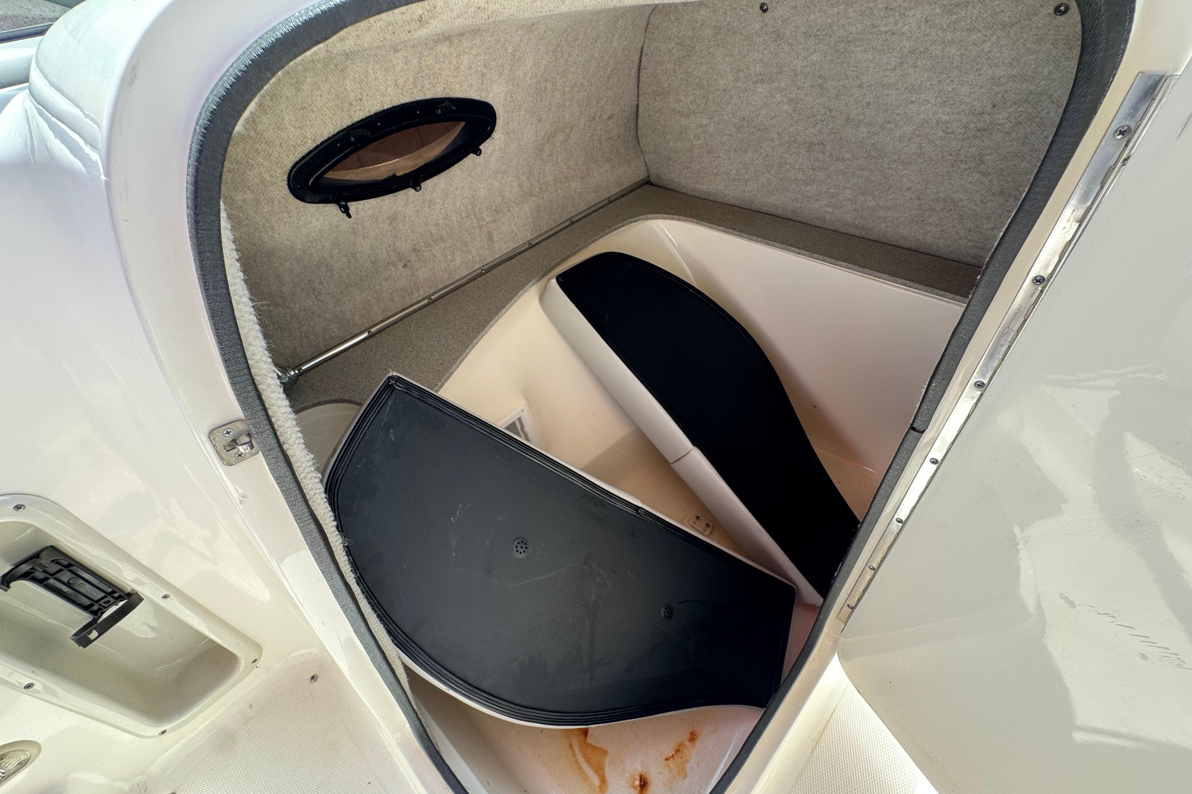 Storage compartment in a 2010 Bryant 255 boat, featuring a small window and carpeted interior.
