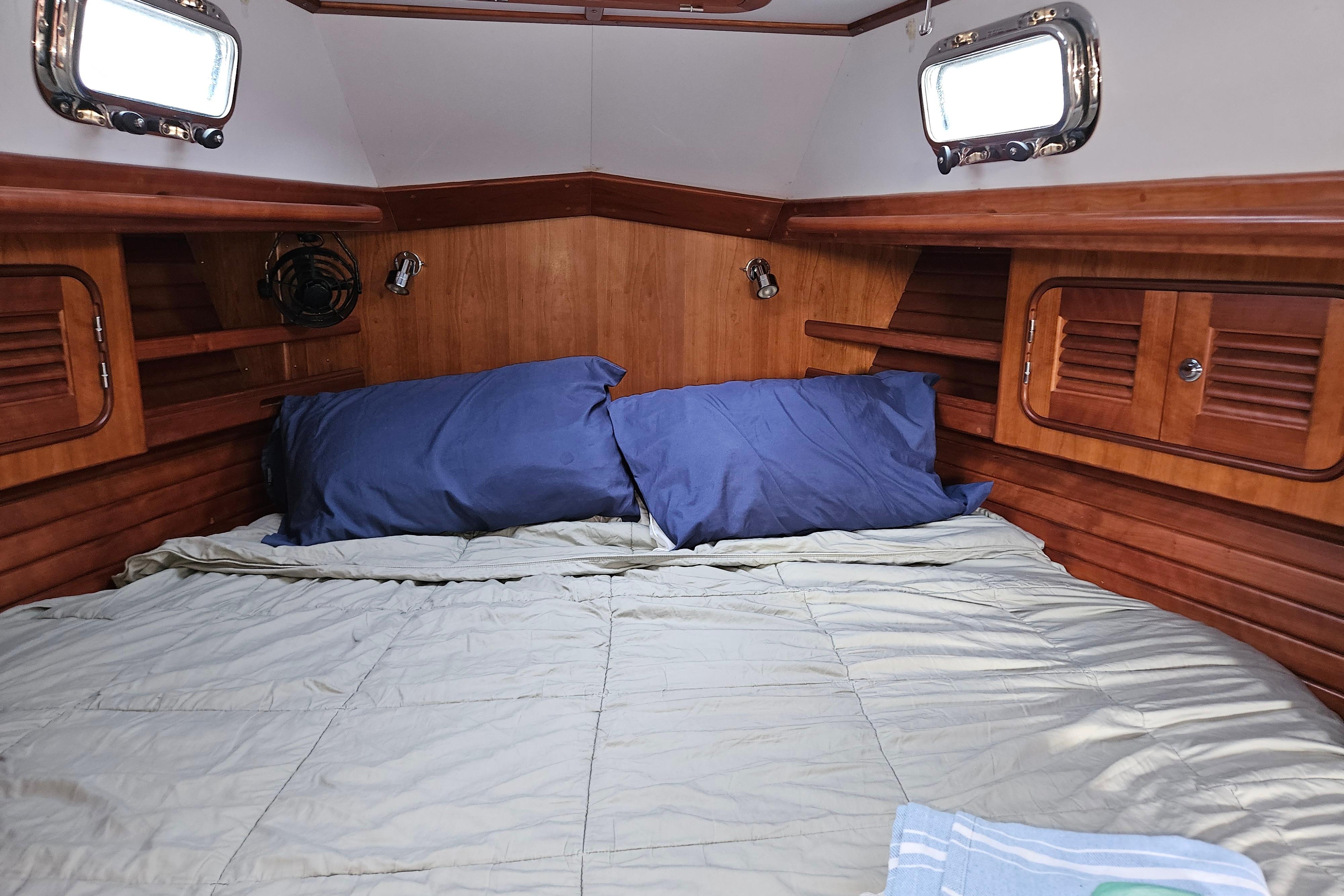Cozy cabin interior of 2013 Passport 470 Center Cockpit sailboat with wooden finish and bedding.