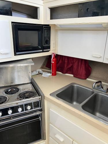 1985 Cruisers Yachts 338 Chateau Vee kitchen with stove, microwave, sink, and fire extinguisher.