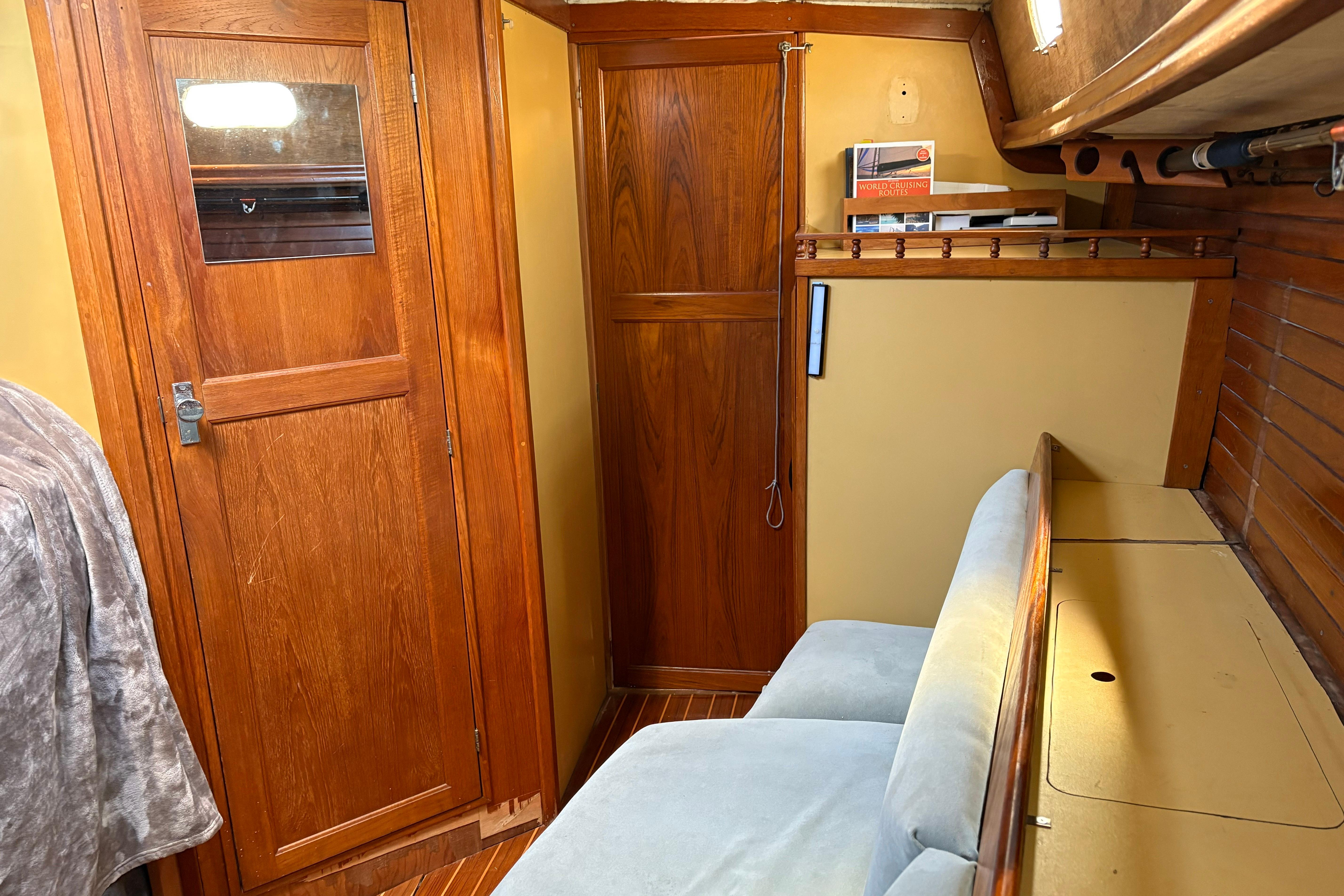 Interior of 1973 Jensen Marine Cal-46 sailboat with wooden cabinetry and cozy seating.
