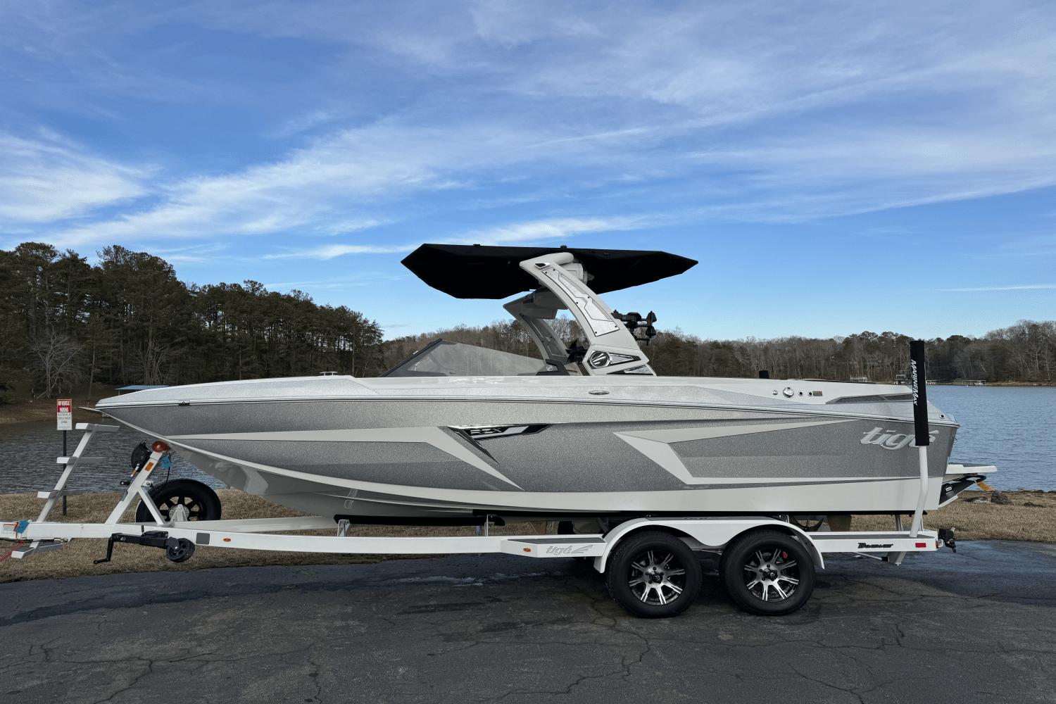 2024 Tigé RZX22 boat on trailer by a lake, featuring sleek design and modern amenities.