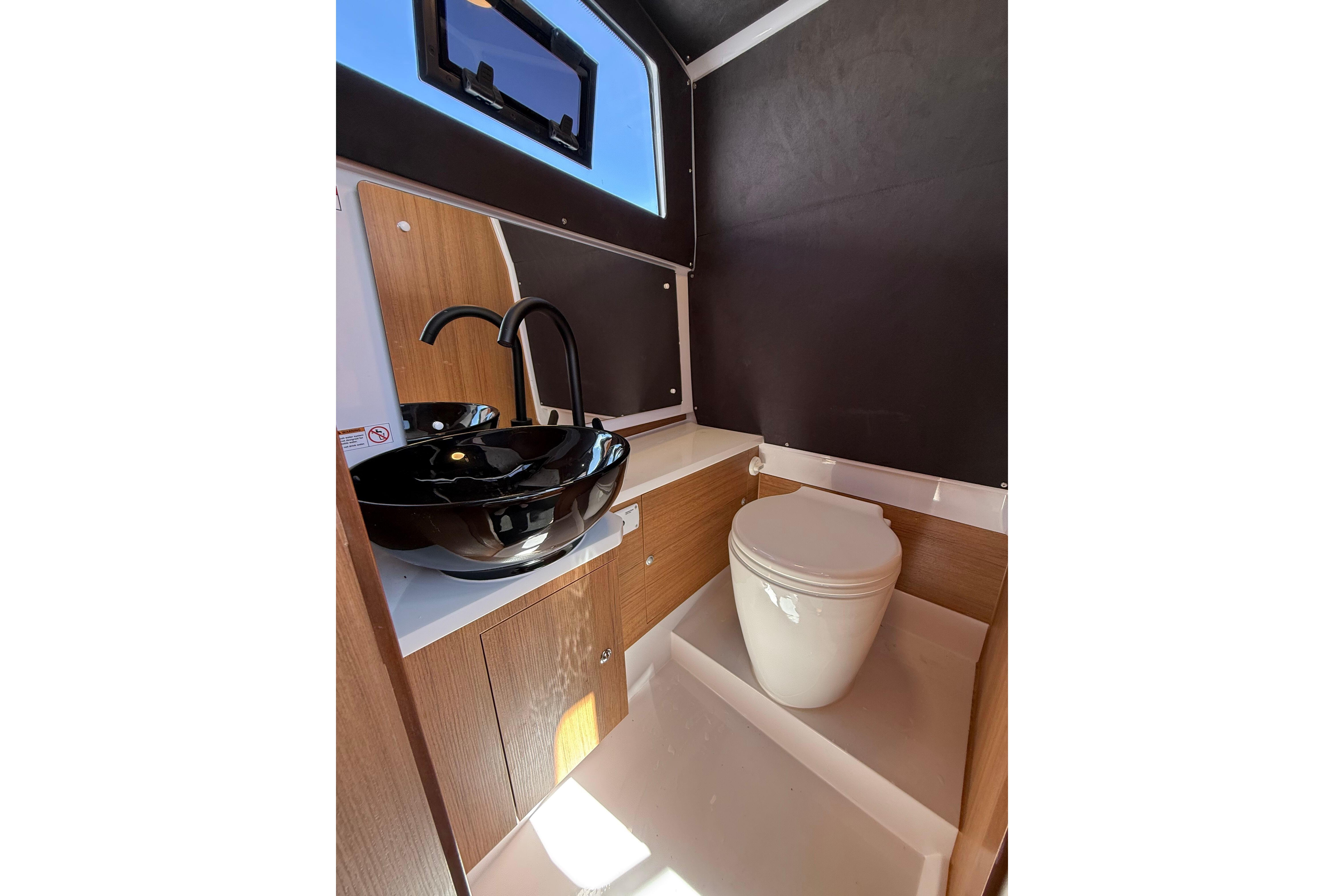 Modern yacht bathroom with sleek black sink and compact toilet, VIRTUE YACHTS V10 TOP 2026.