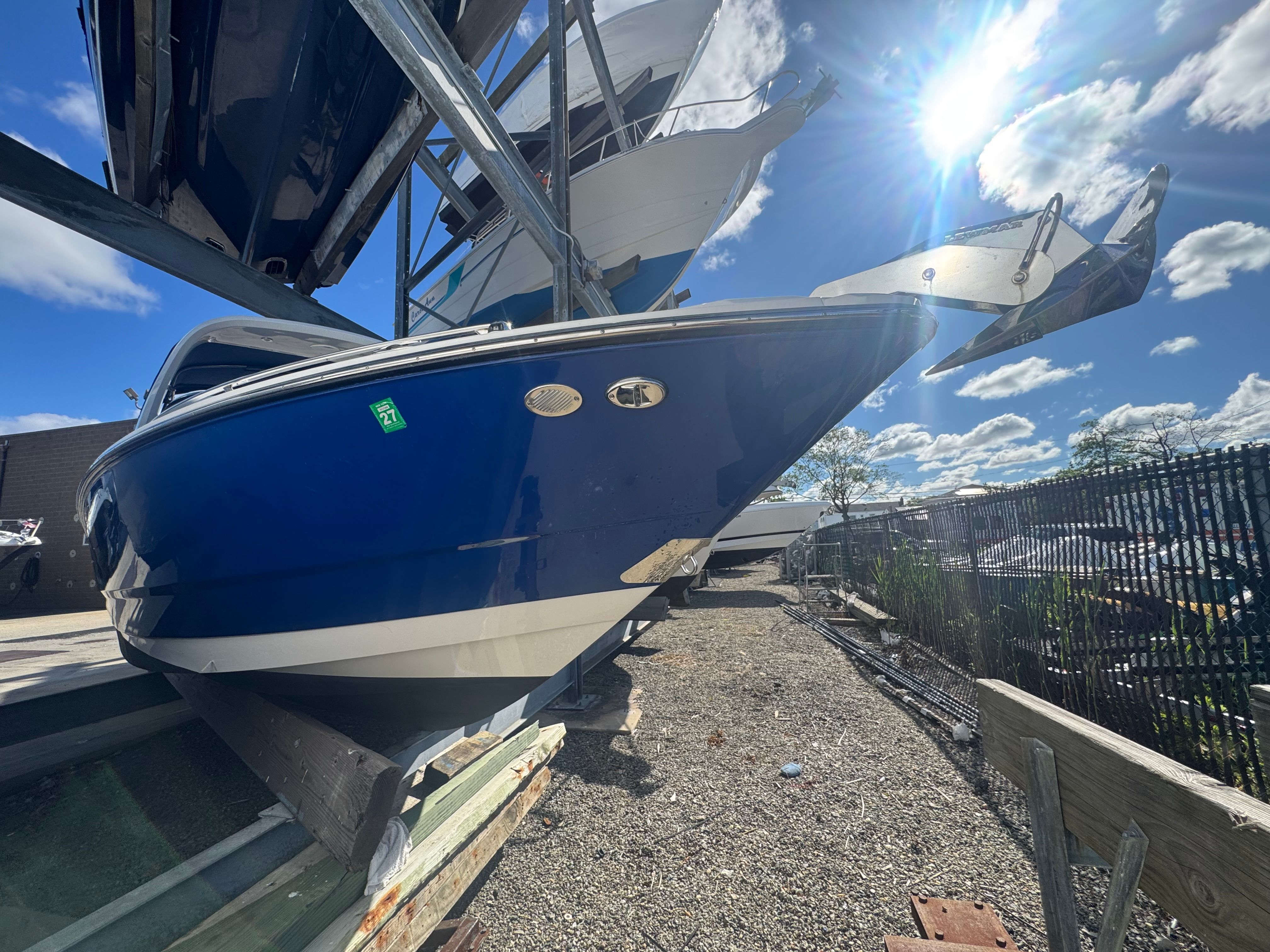A blue 2019 Monterey 298SS Super Sport boat is on a dry dock under a sunny sky.