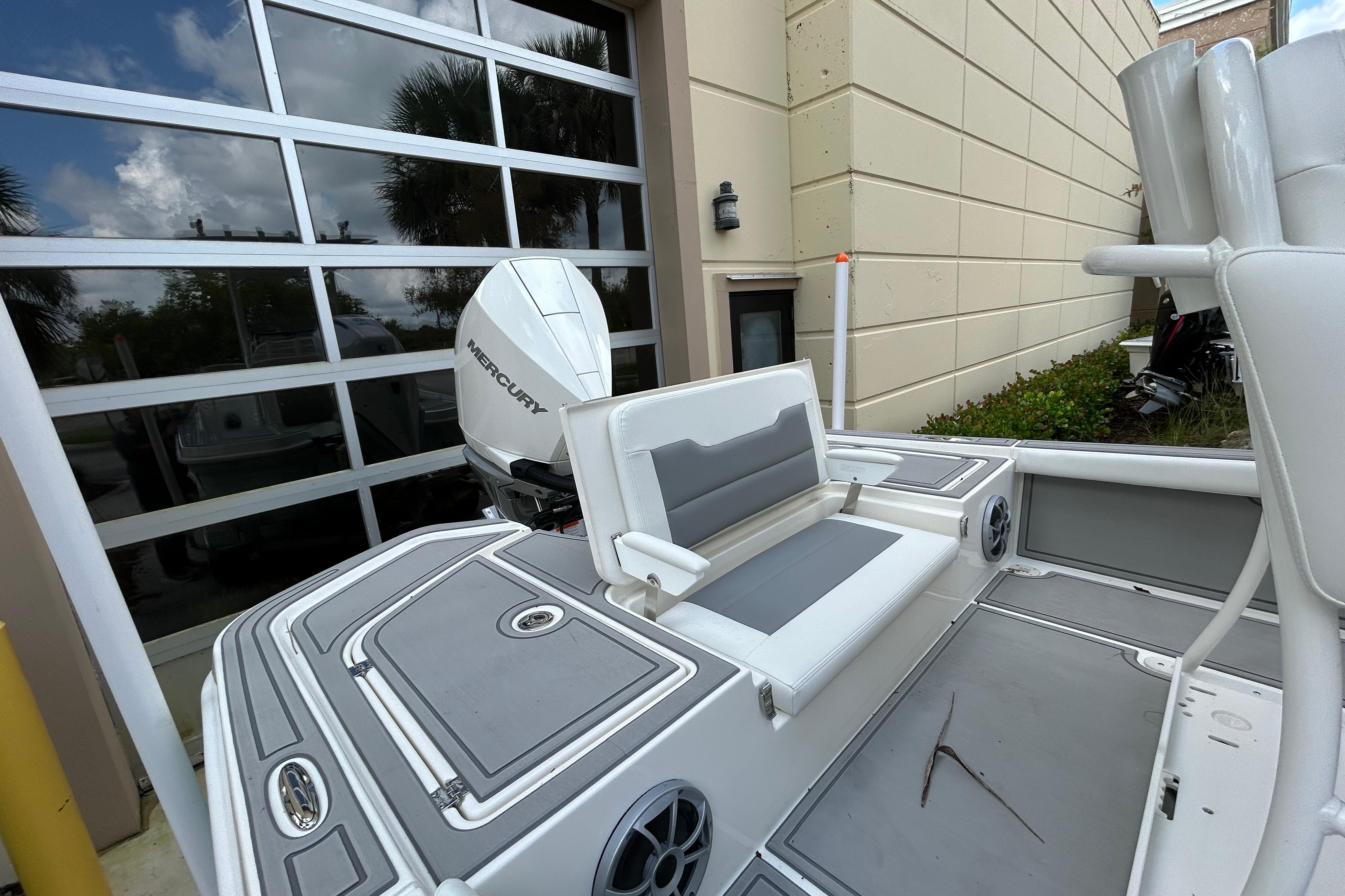 2025 Mako 24 APEX boat with Mercury engine, parked near a garage.