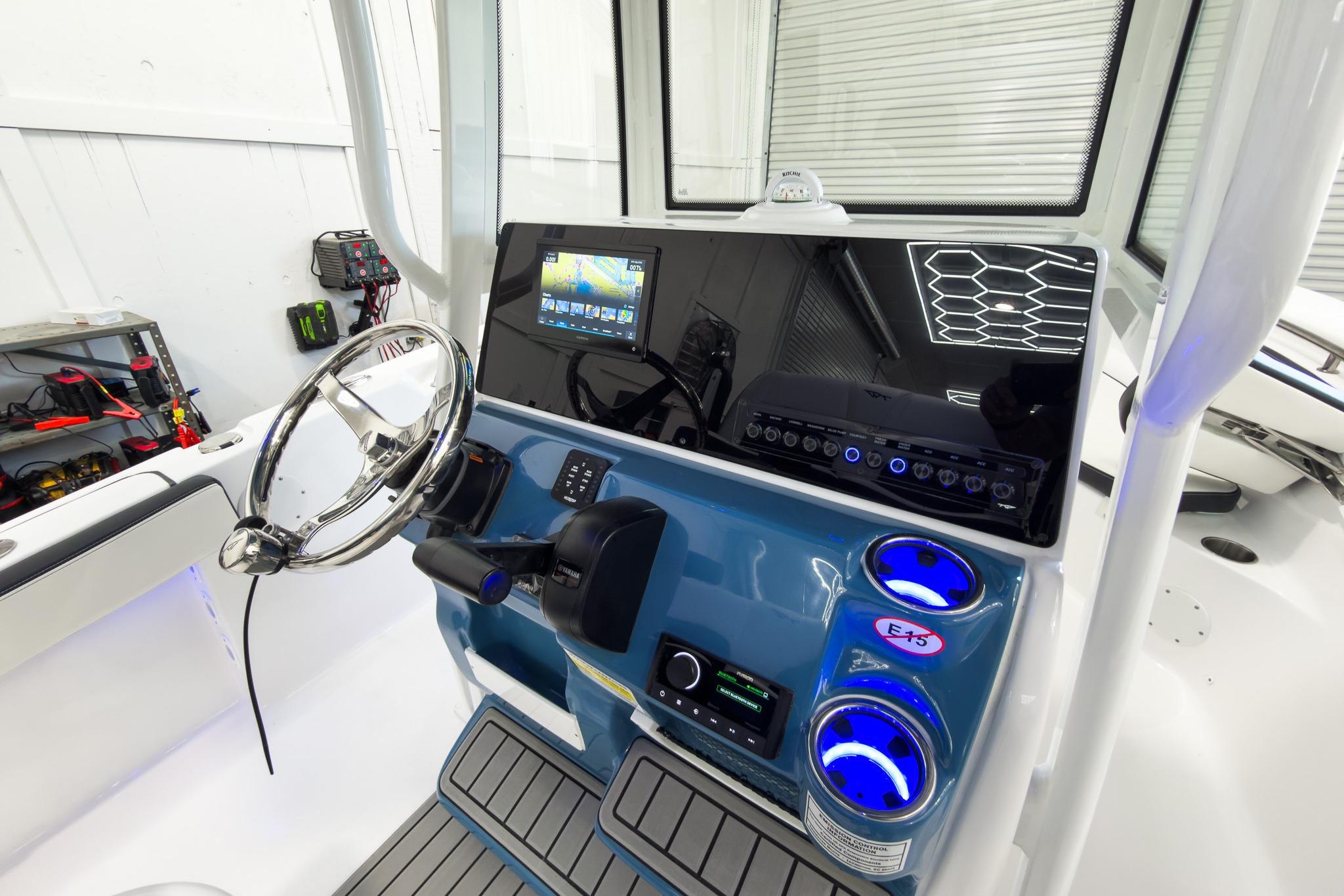 The image shows the helm of a Tidewater 220 LXF boat. It features a modern steering wheel, large display, and various controls.