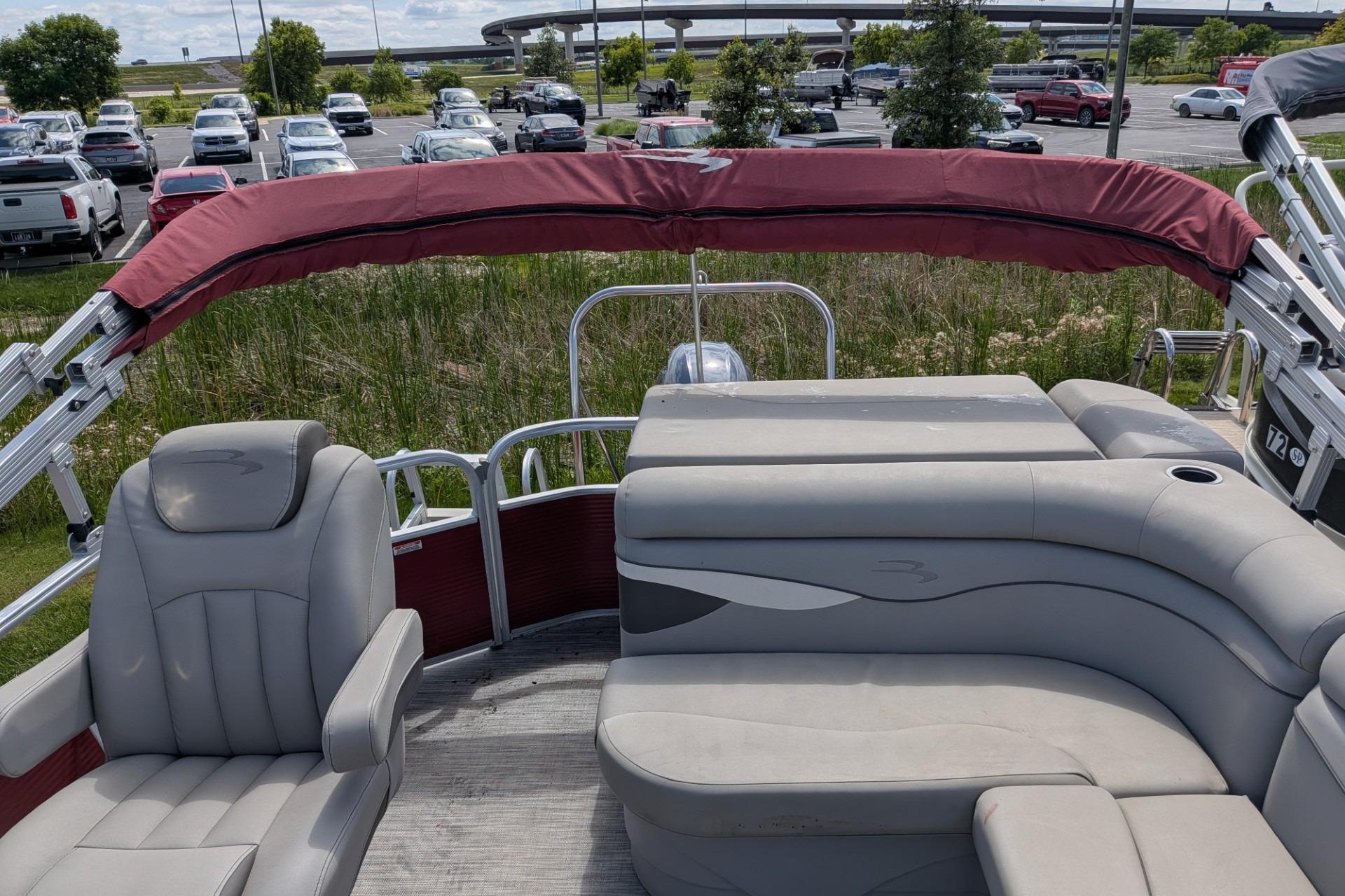 2021 Bennington 205SL pontoon boat with gray seating and red canopy in a parking lot.