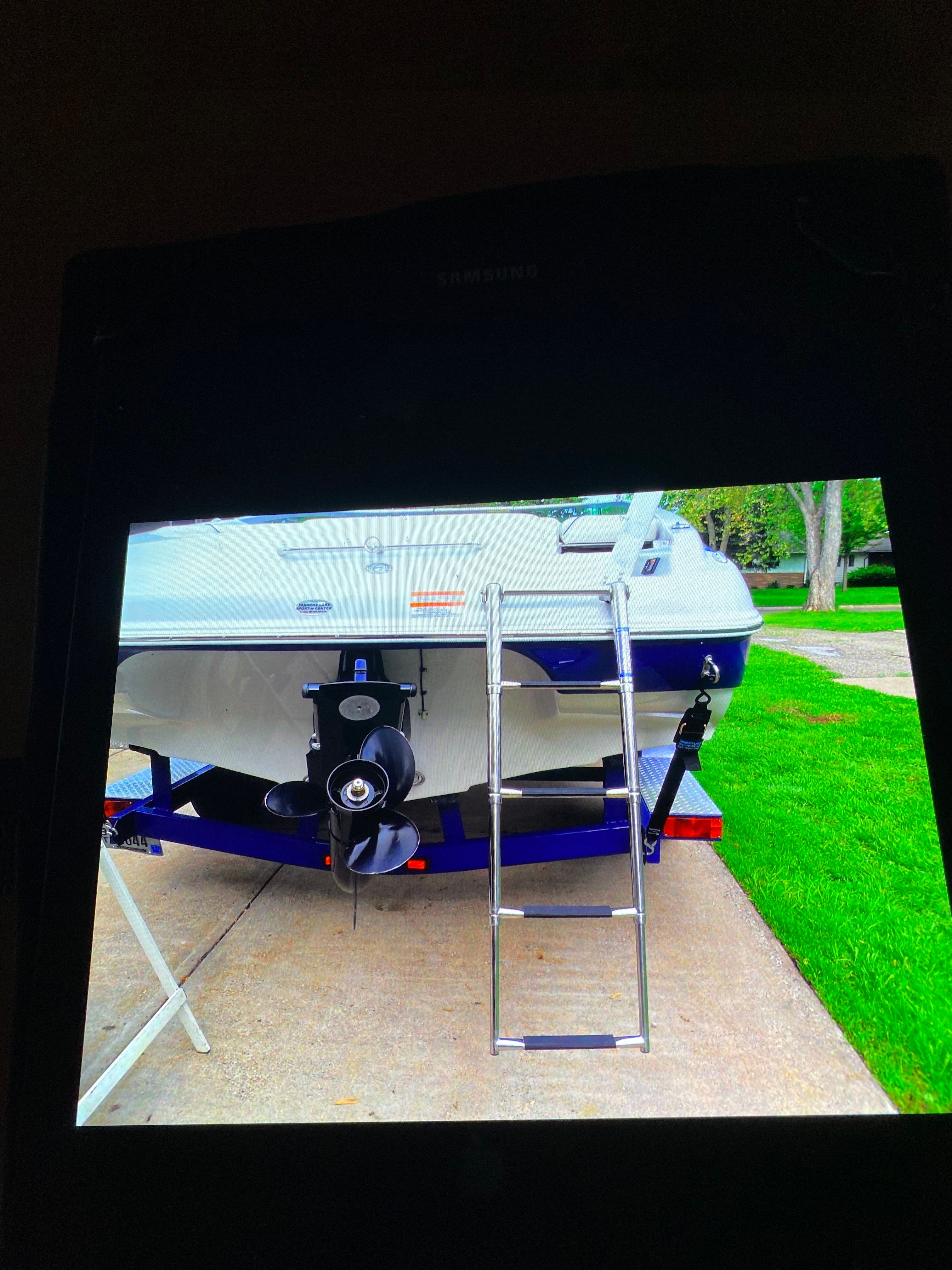 A Crownline 21 bowrider boat on a trailer, featuring a ladder and propeller.