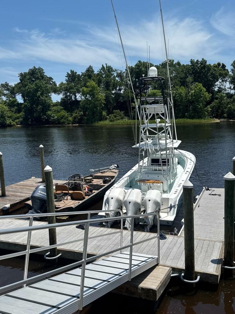 2012 Contender 39ST boat docked by a river, surrounded by lush greenery.