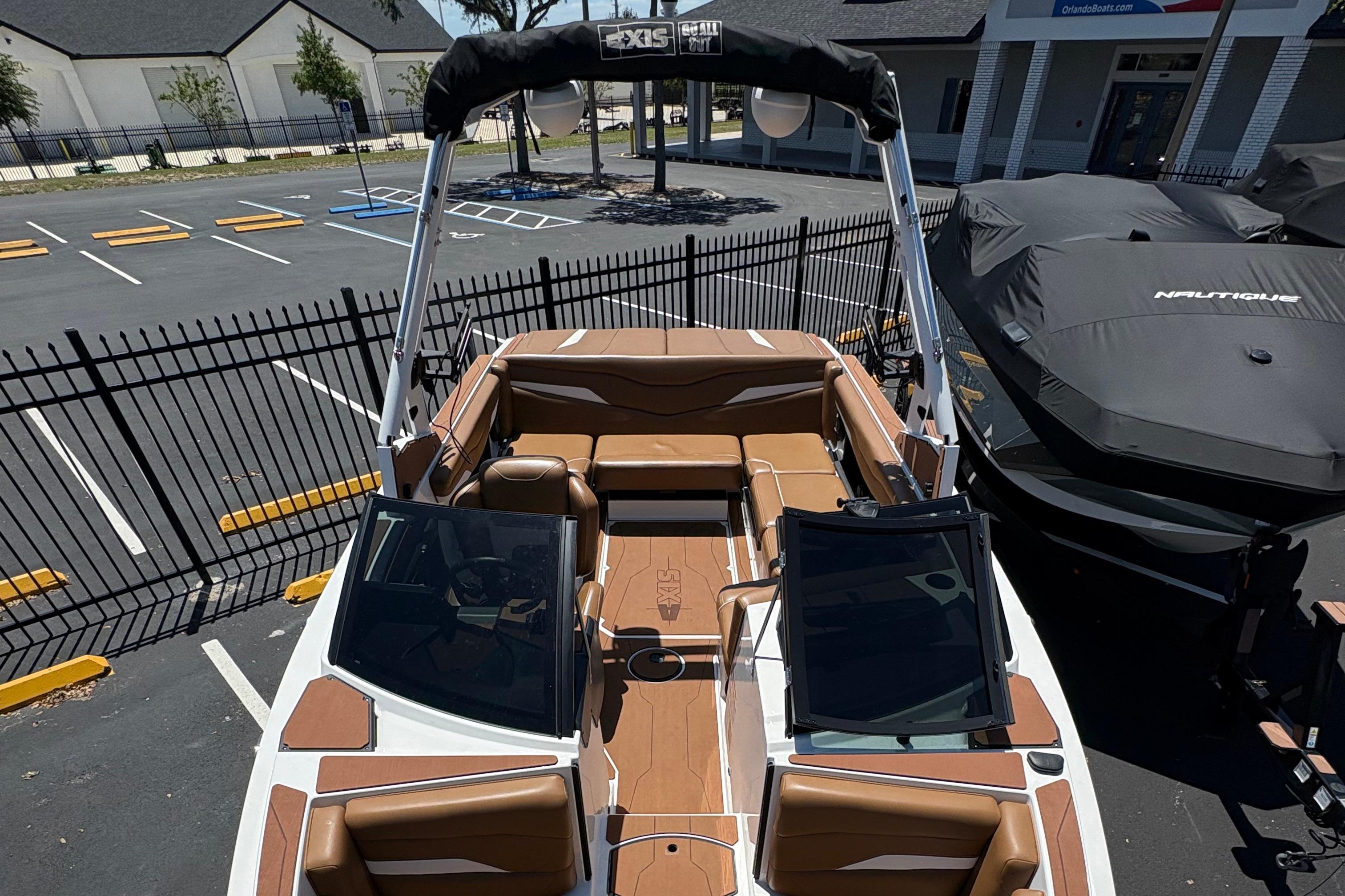 2025 Axis T220 boat with brown interior, parked in a lot near a fence.