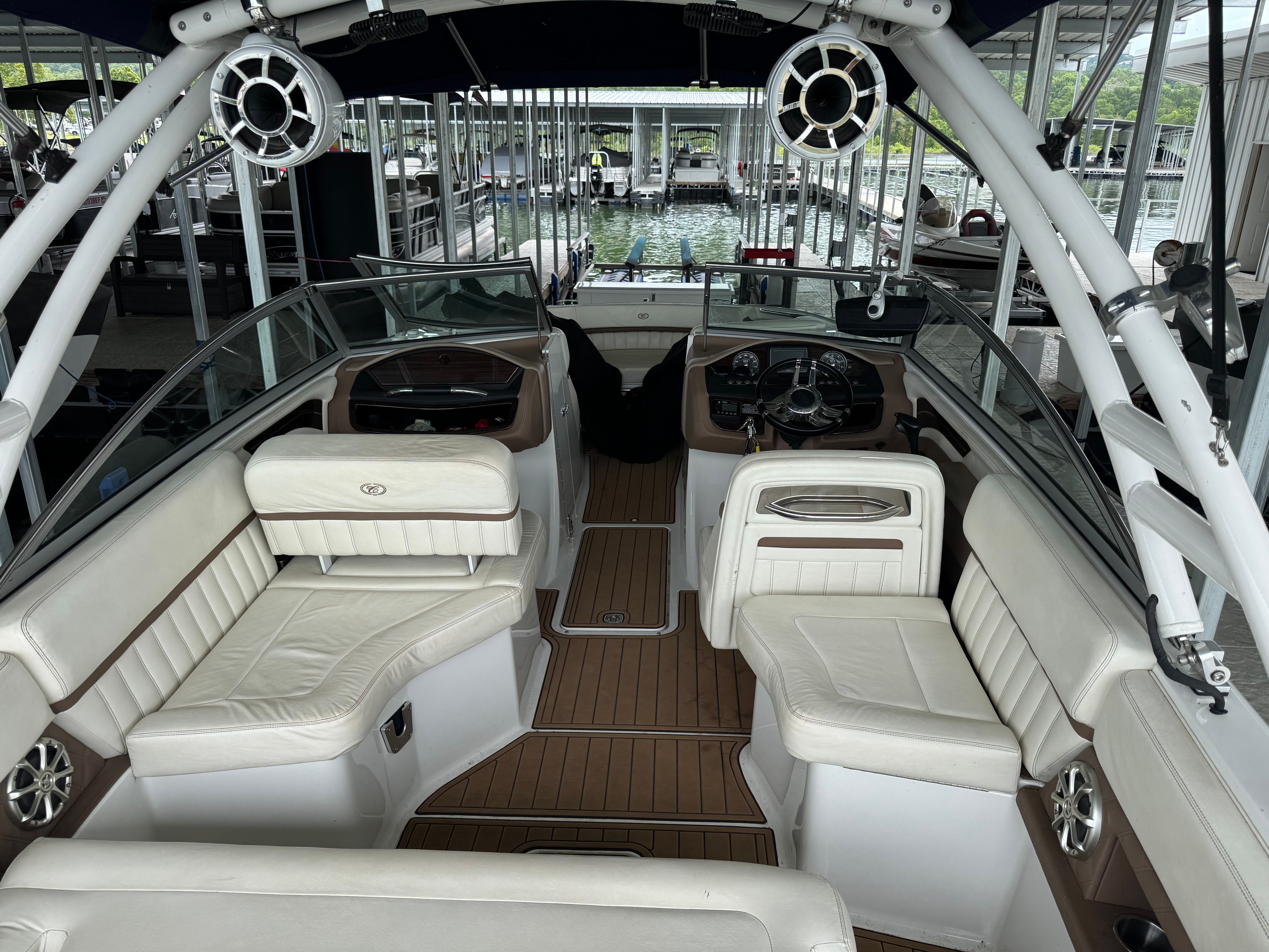 The image shows the cockpit of a 2011 Cobalt A25 boat with white leather seats and wood flooring.