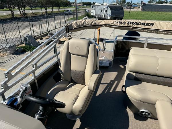 2025 Sun Tracker 24 Sportfish XP3 pontoon boat interior with beige seating and steering console.