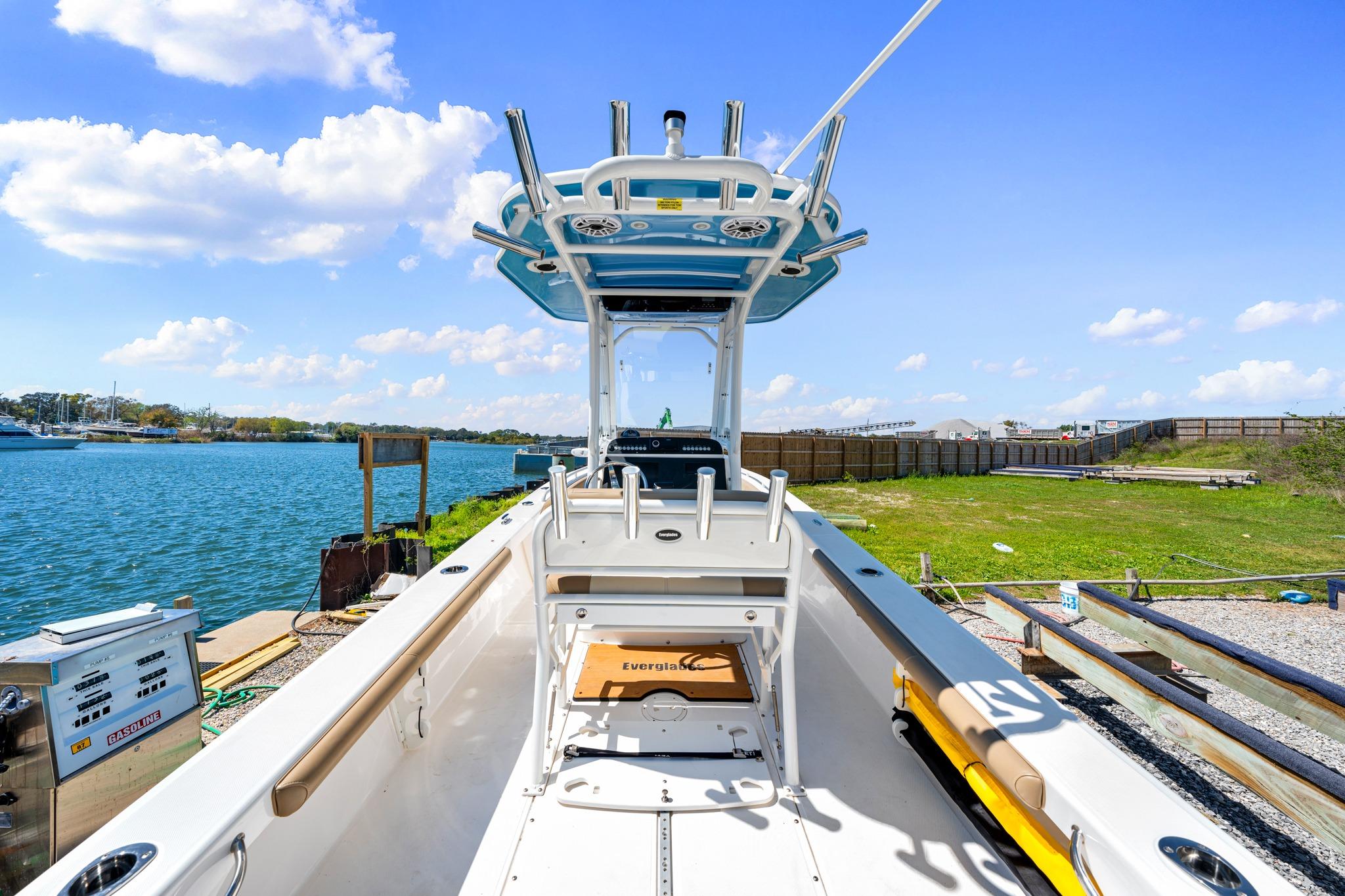 2023 Everglades 243 Center Console boat docked by a scenic waterfront under a clear blue sky.