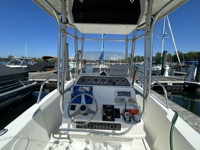 The image shows the helm of an Aquasport Osprey 250 boat docked at a marina.