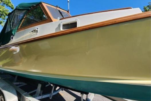 1985 Wasque Down East Cruiser boat with green canopy on trailer under clear blue sky.