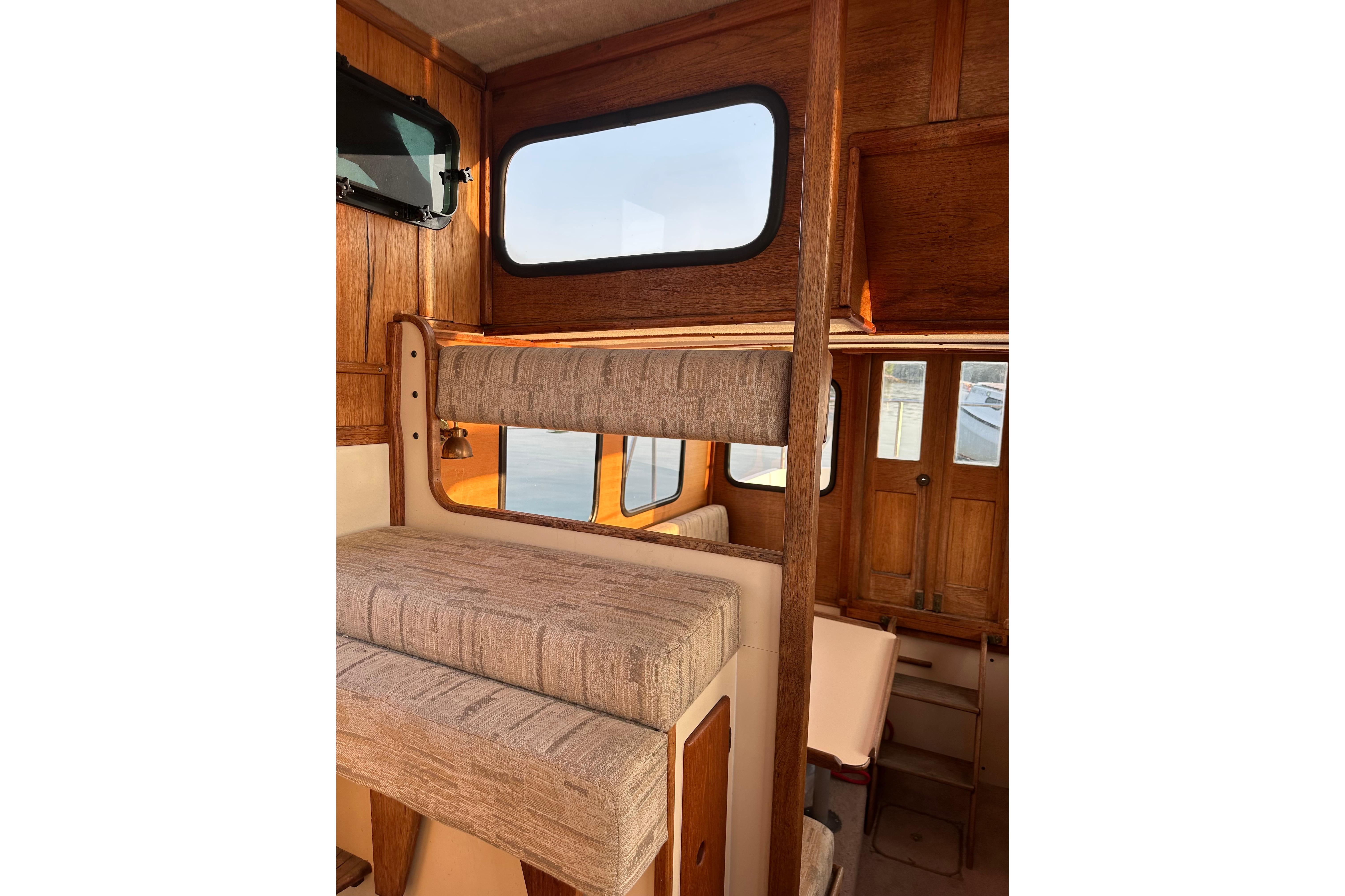 Interior of a 1985 Nordic Tug 26, featuring wooden paneling and cushioned seating.