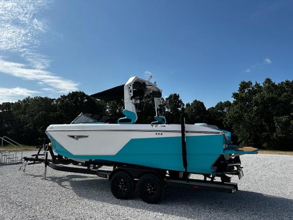 2022 Nautique S23 boat on trailer, turquoise and white, parked outdoors.