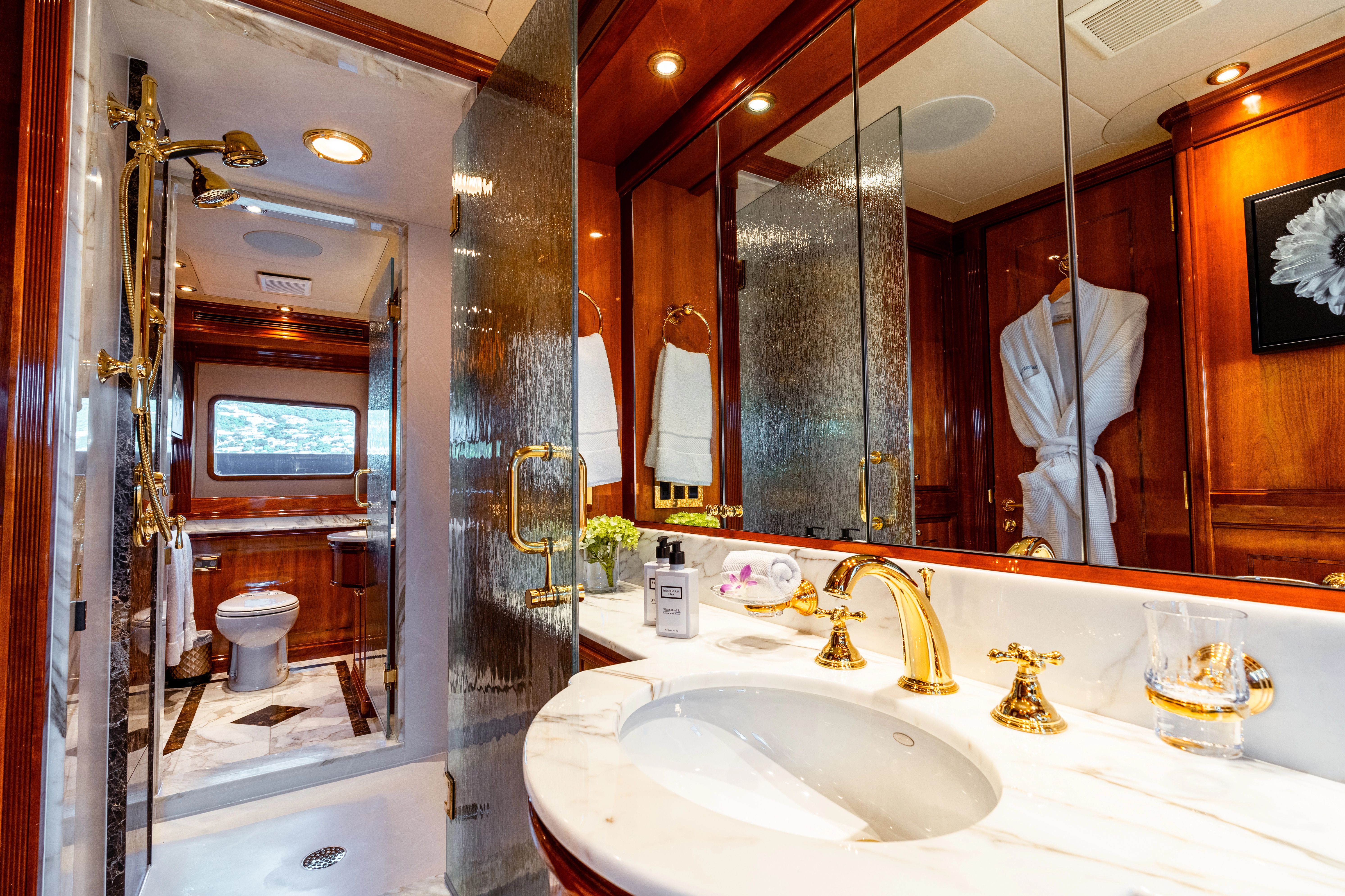 Luxurious bathroom with marble countertop, gold fixtures, and wood paneling on a yacht.