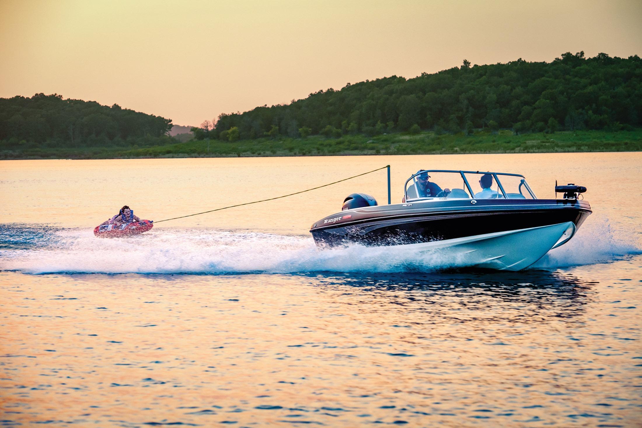 2026 Ranger 1850MS boat towing a person on a tube across a serene lake at sunset.