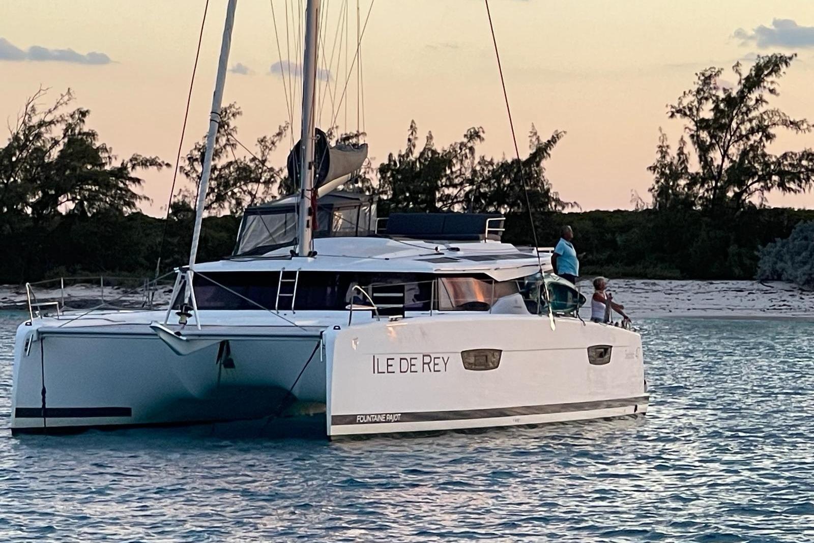 2020 Fountaine Pajot Saona 47 catamaran anchored near a scenic beach at sunset.