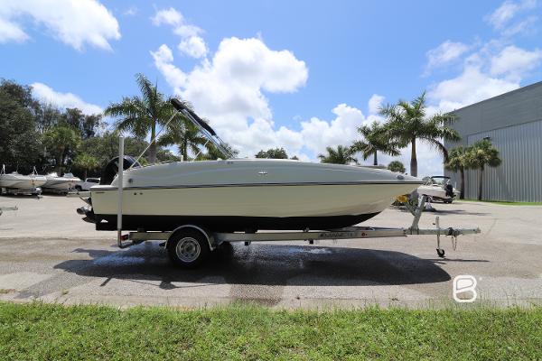 2018 Bayliner 210 DB boat on trailer, parked outdoors with palm trees and blue sky.