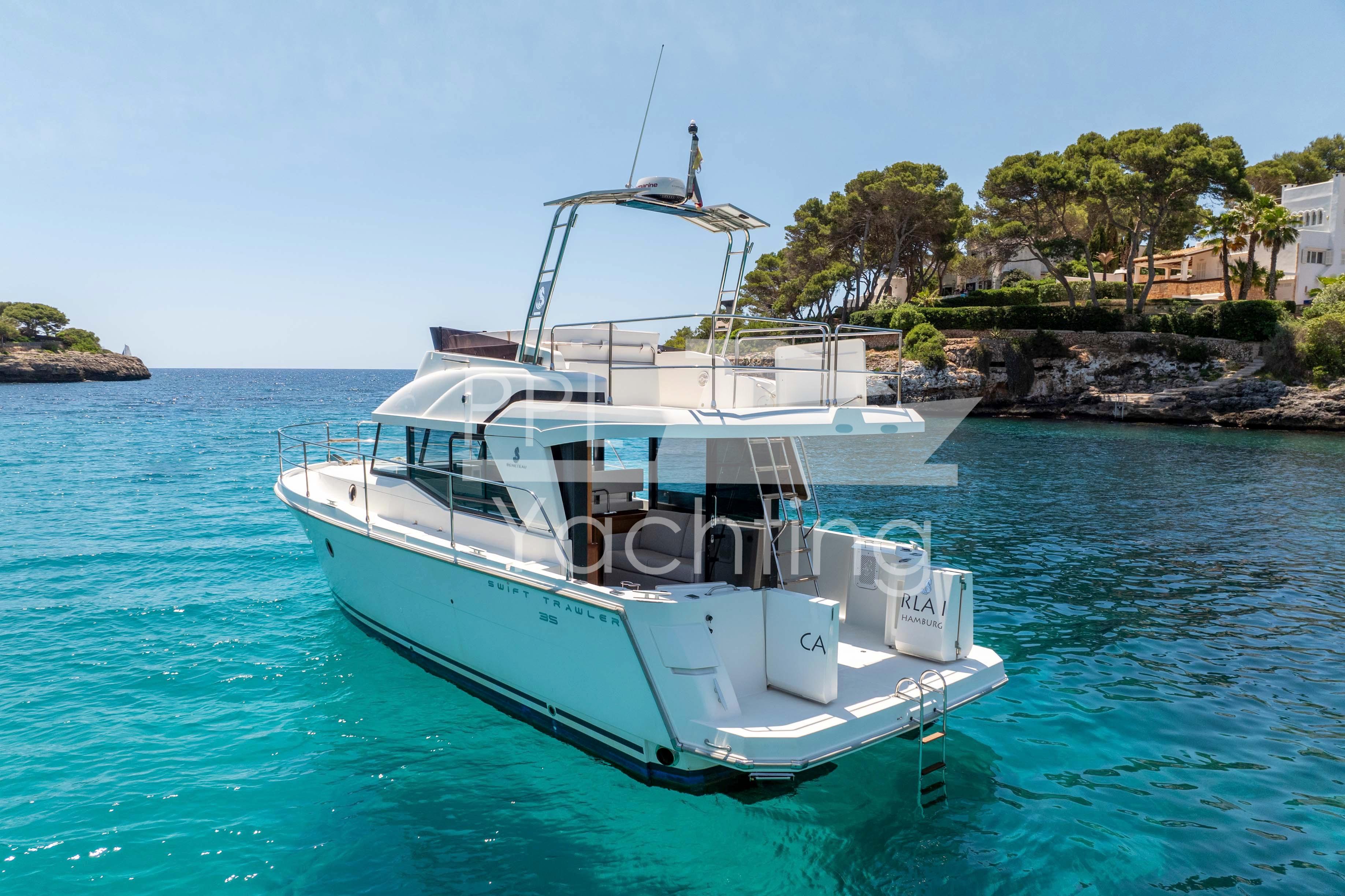 2019 Beneteau Swift Trawler 35 on clear blue water near a rocky shoreline.