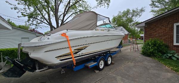 1999 Sea Ray 280 SS boat on trailer, parked in driveway, covered with tarp.