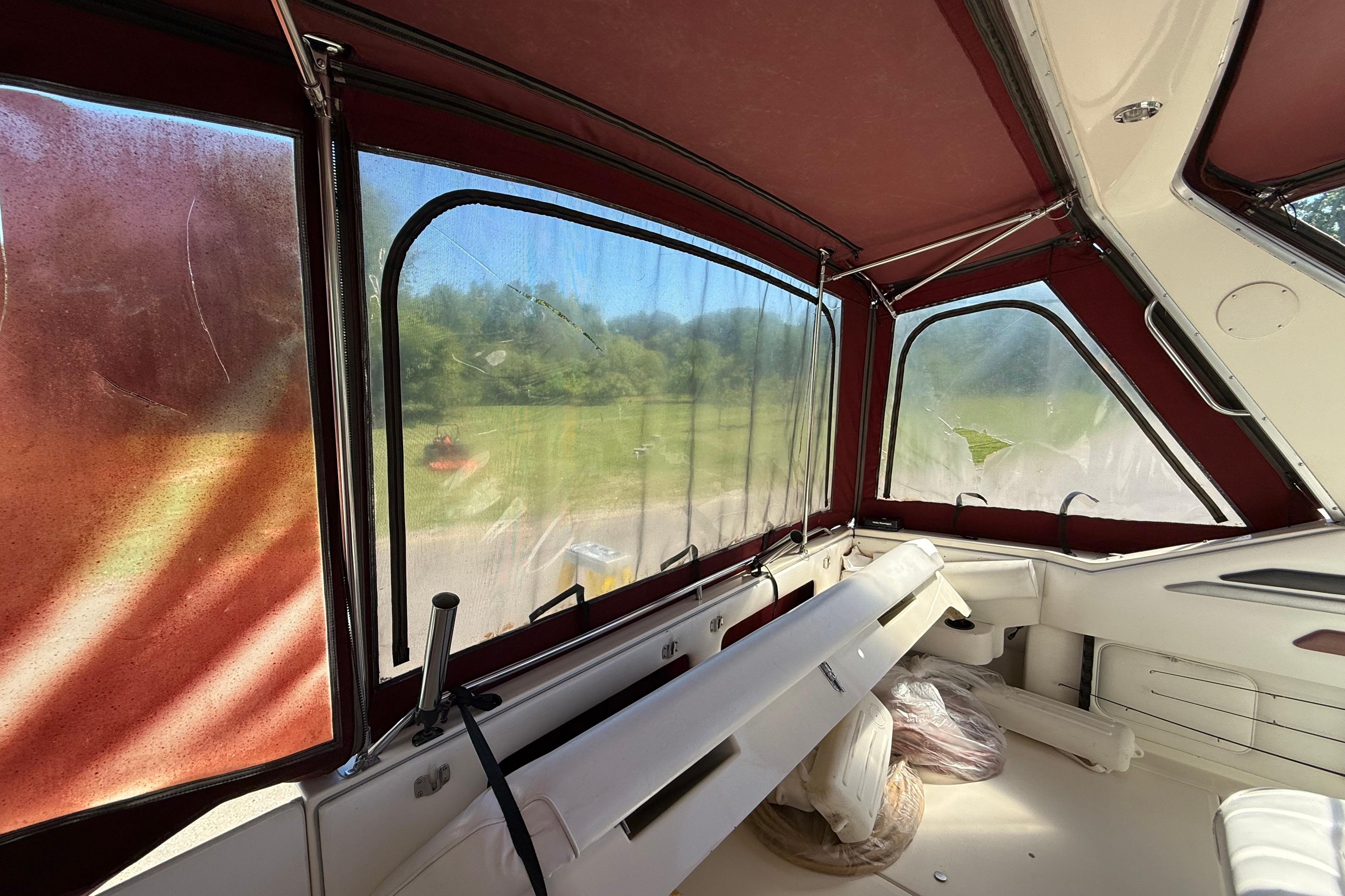 Interior view of a 1990 Sea Ray 310 Express Cruiser with red canopy and clear windows.