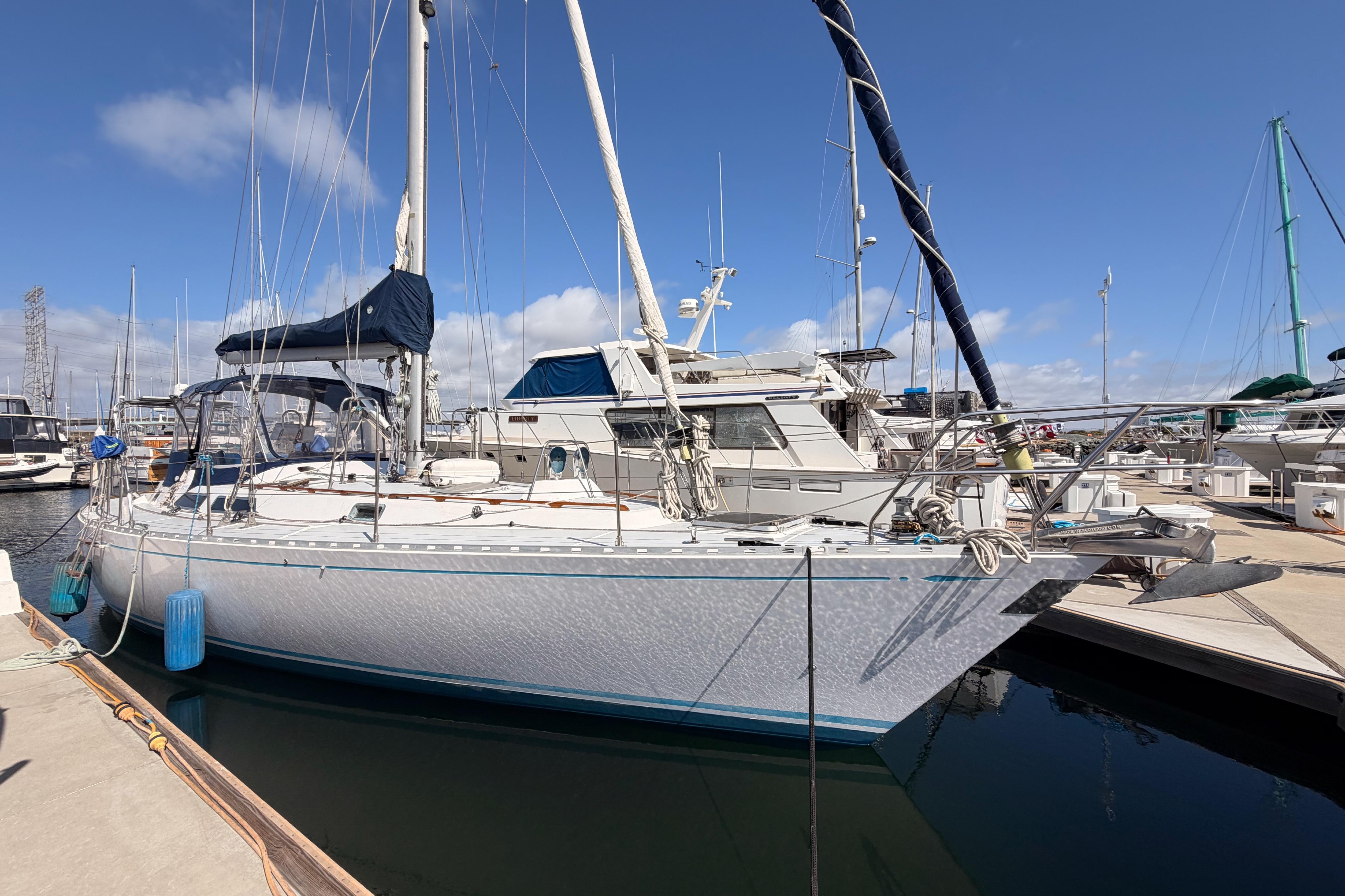 Sailboat docked at marina, Hylas 51 model from 1991, under clear blue sky.